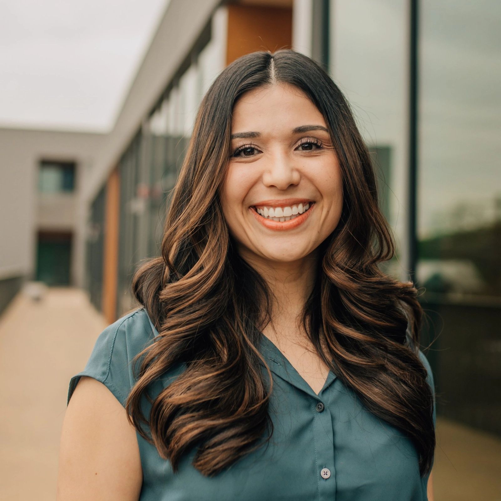 gabriela is smiling for the camera in front of a building .
