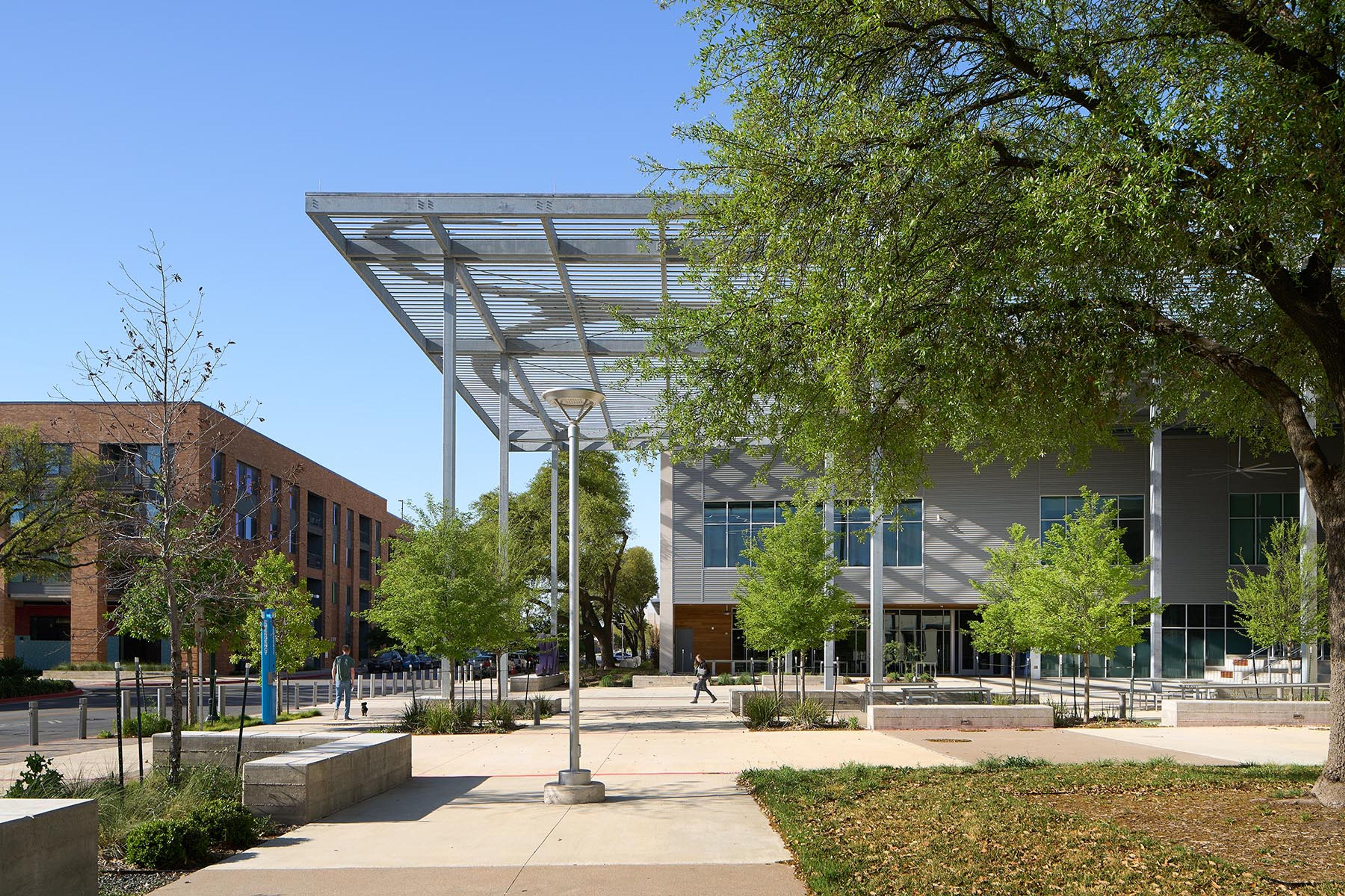 a man is walking in front of a large building with a canopy over it .