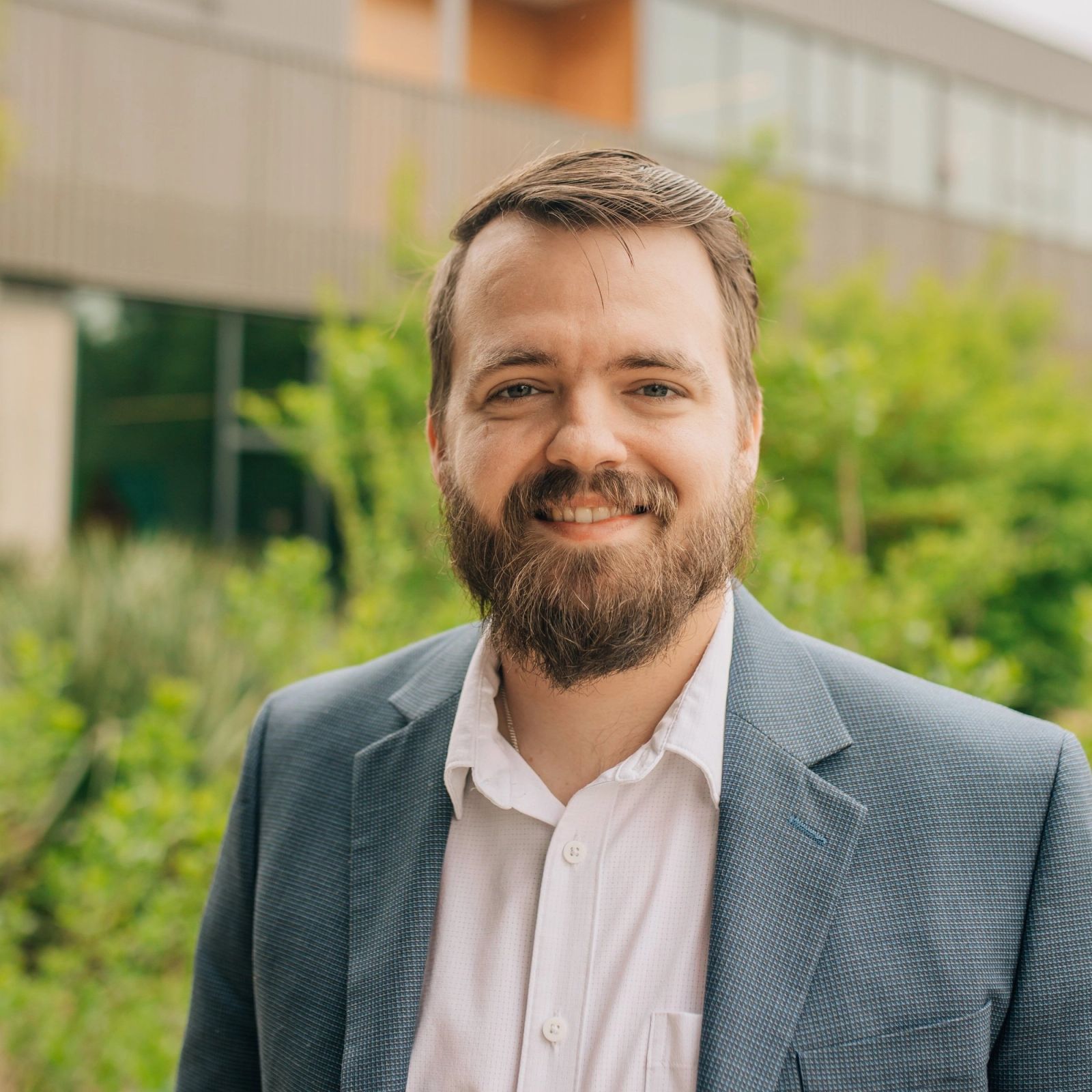 Michael is wearing a suit and smiling for the camera .