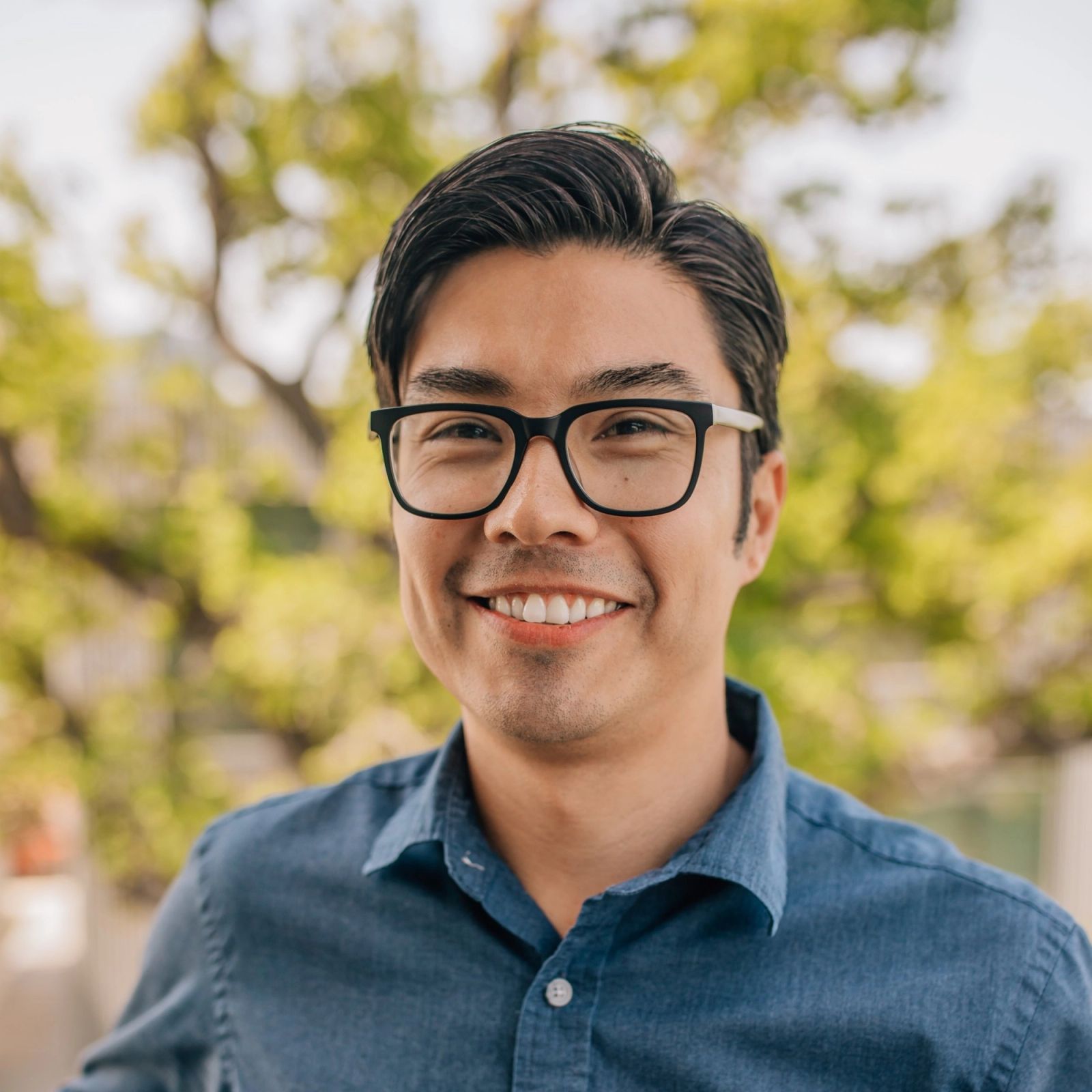 Chris wearing glasses and a blue shirt is smiling for the camera .