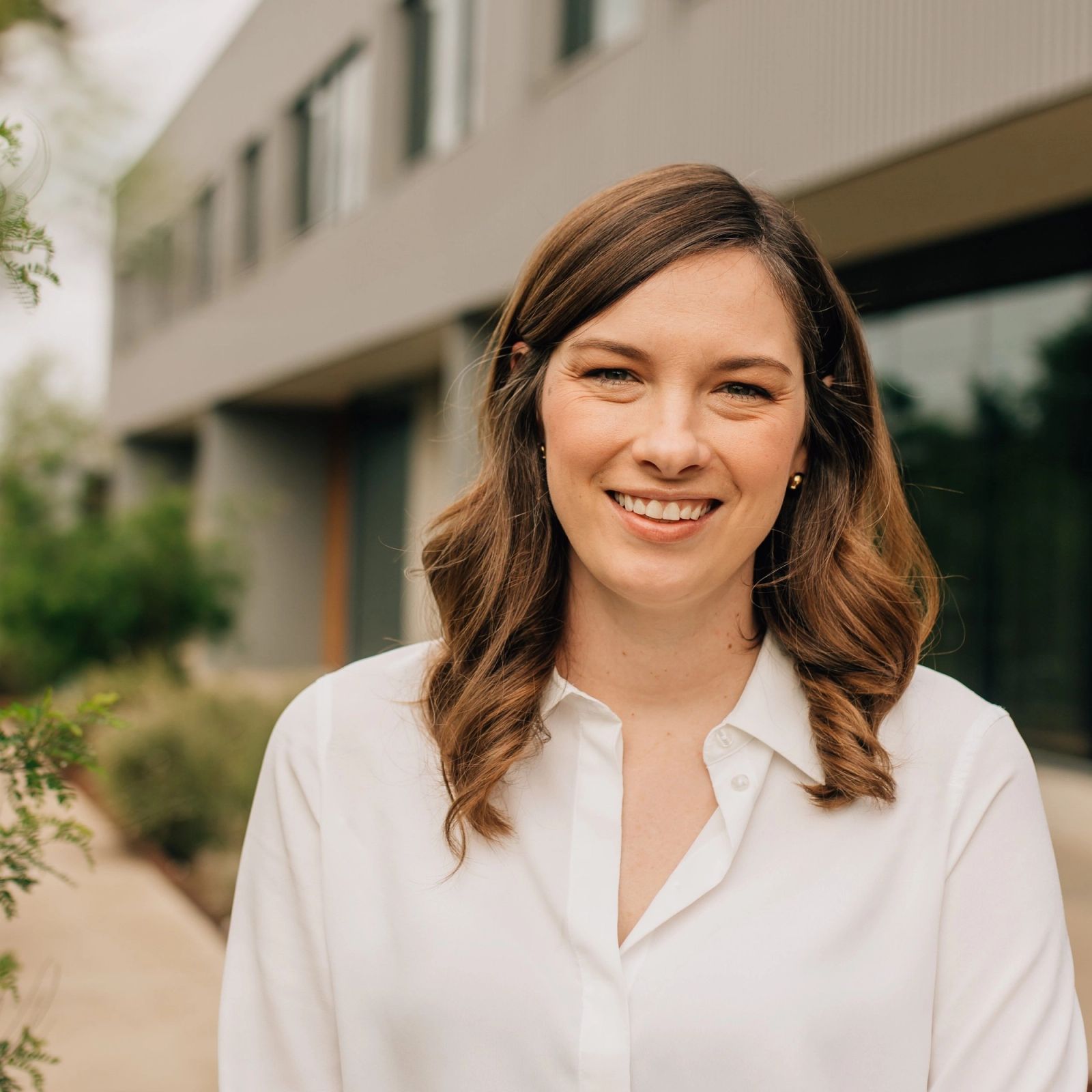 Grace is smiling in front of a building .