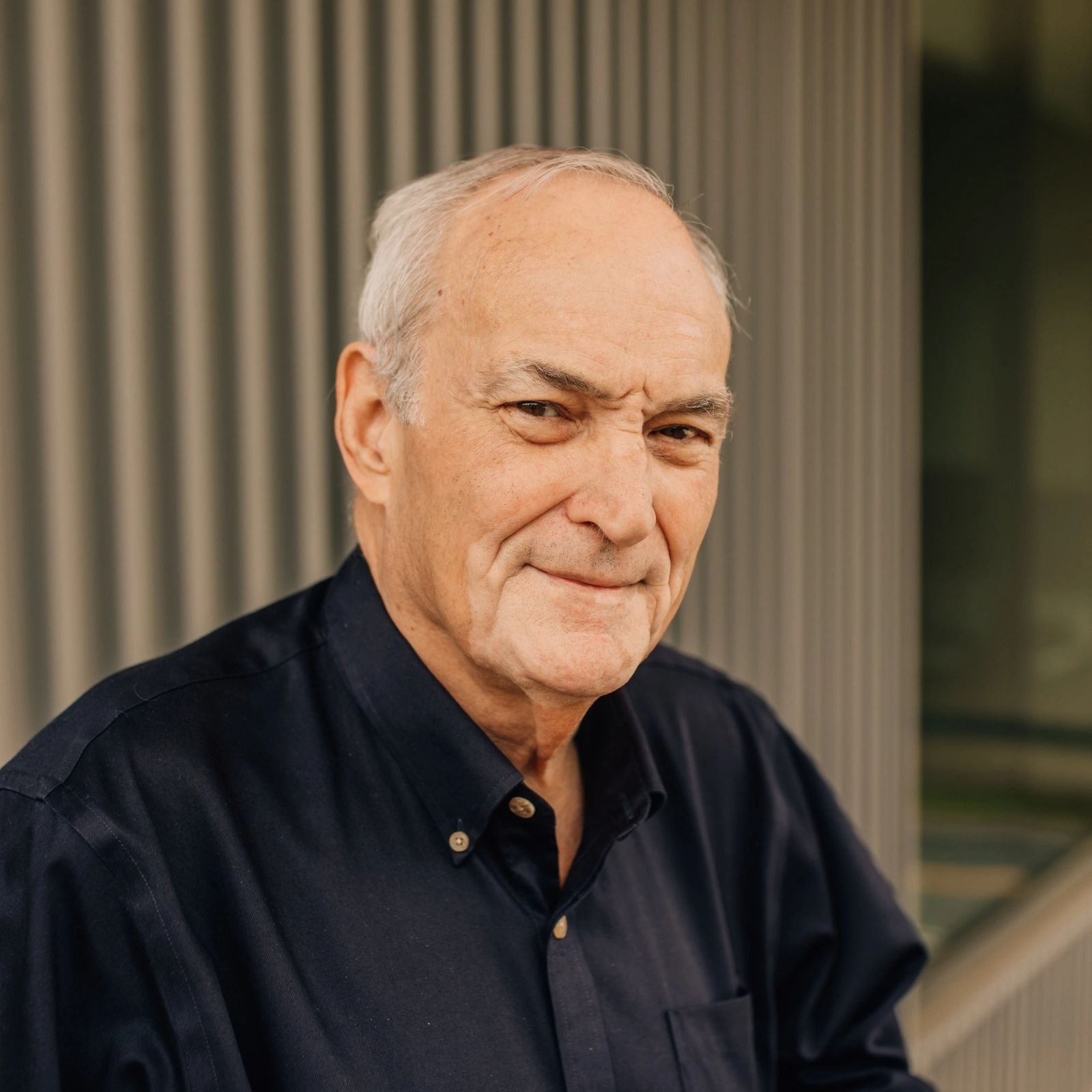 Fred in a blue shirt is smiling for the camera .