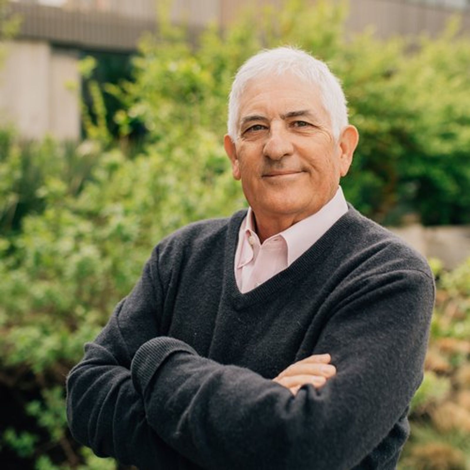 Jay is standing with his arms crossed in a garden .