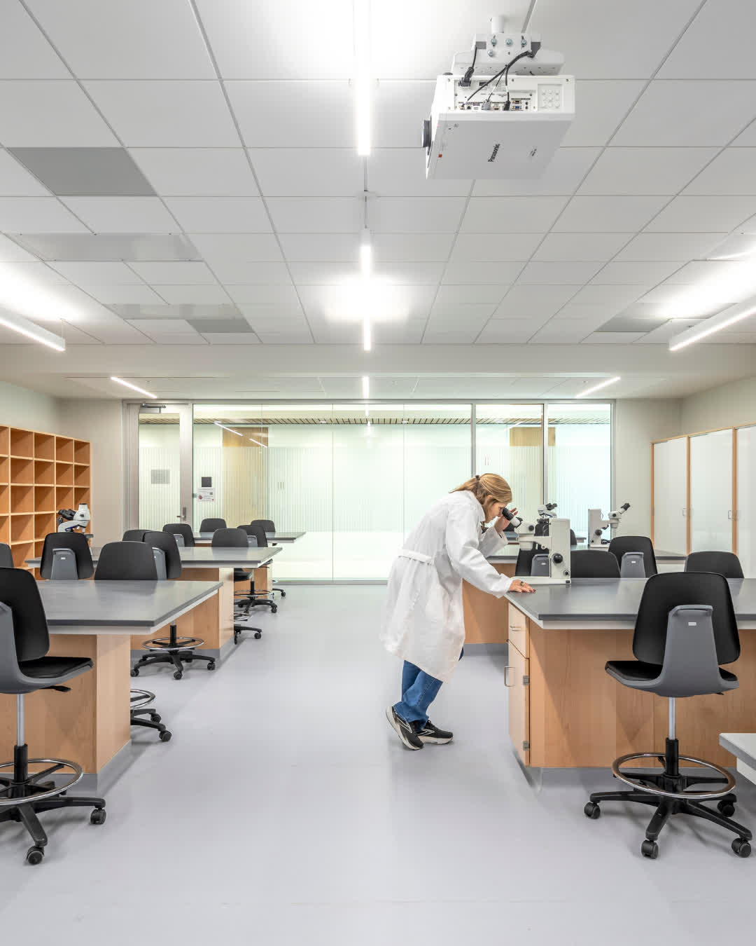 woman looking at microscope in lab