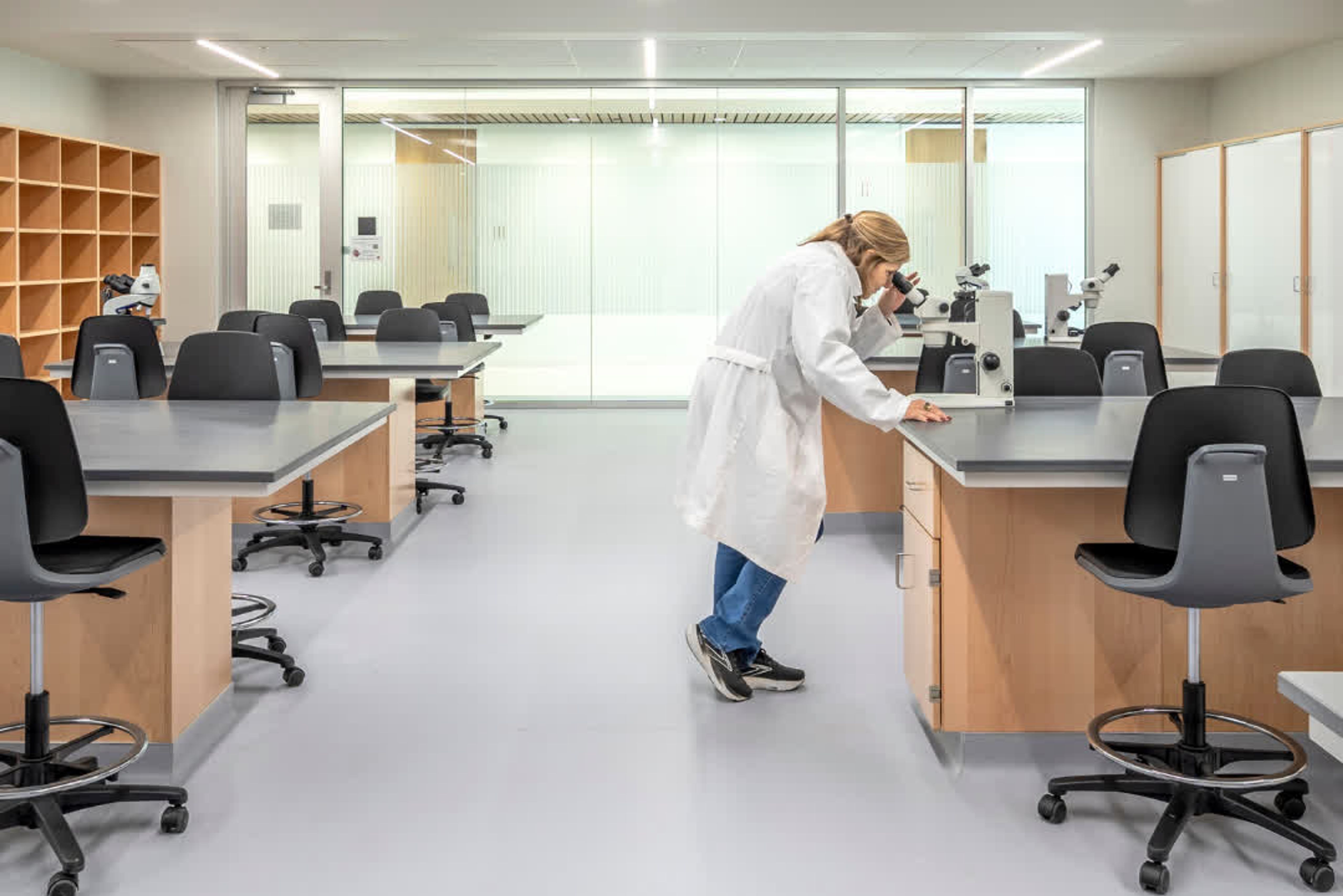 woman looking at microscope in lab