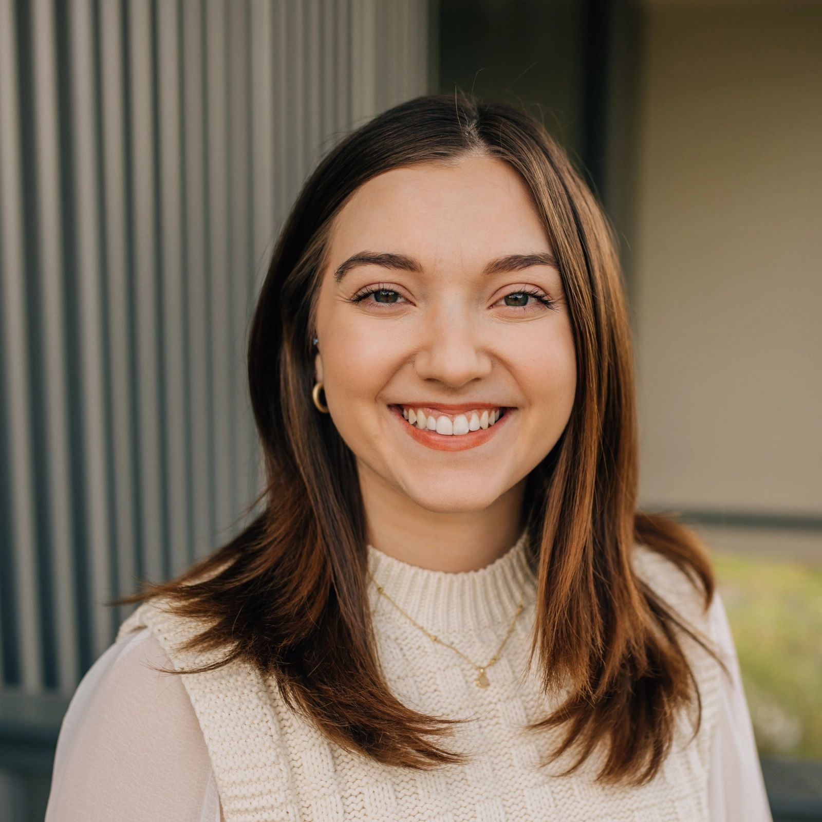 Geneva is wearing a white sweater and smiling for the camera .