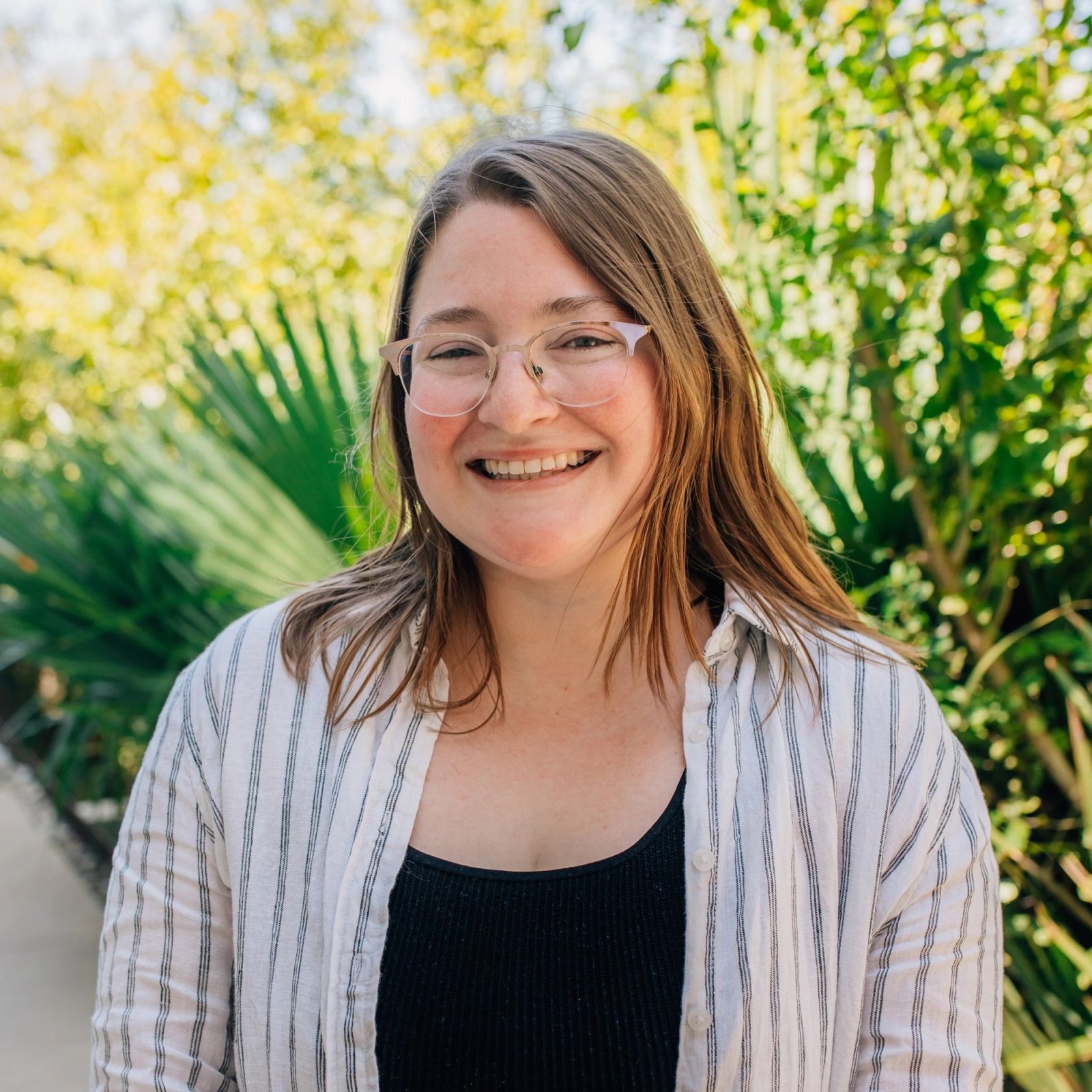 Corey wearing glasses and a striped shirt is smiling for the camera .