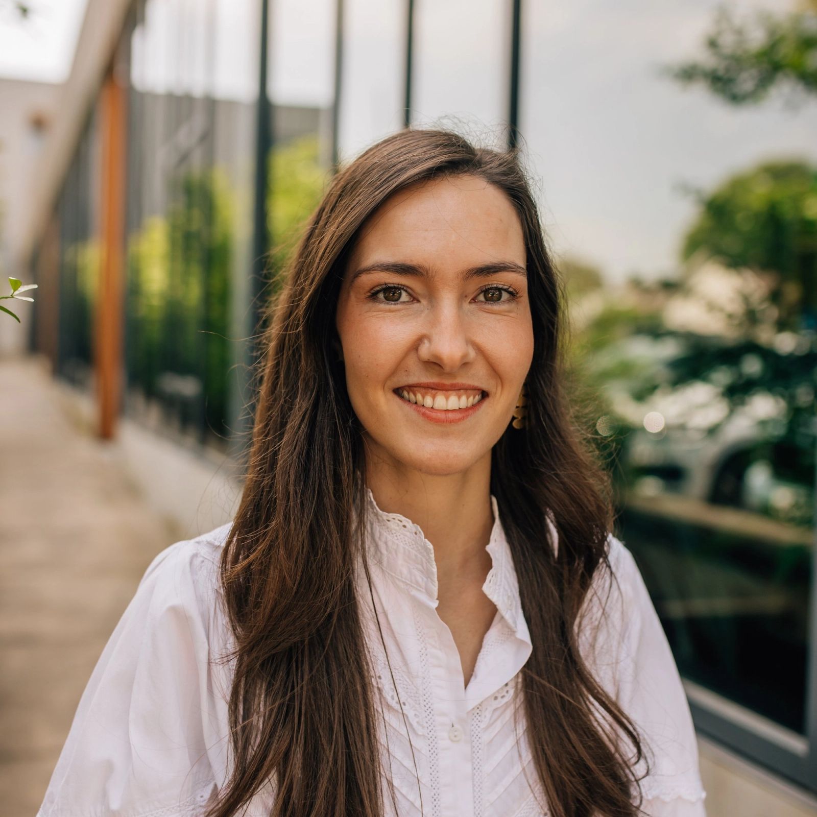 Maria is wearing a white shirt and smiling for the camera .