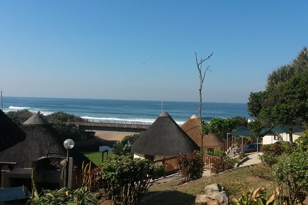 Thatched-roof units at Banana Beach Club on the KwaZulu-Natal South Coast, set in a garden with the beach and sea just beyond