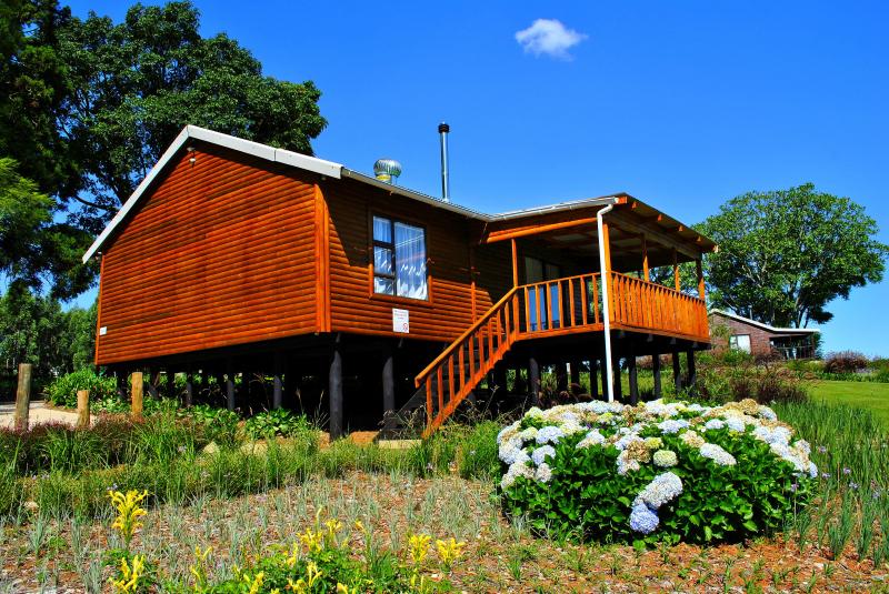 Raised wooden cabin with a covered deck at Forest View Cabins near Tzaneen, set in a garden with hydrangeas