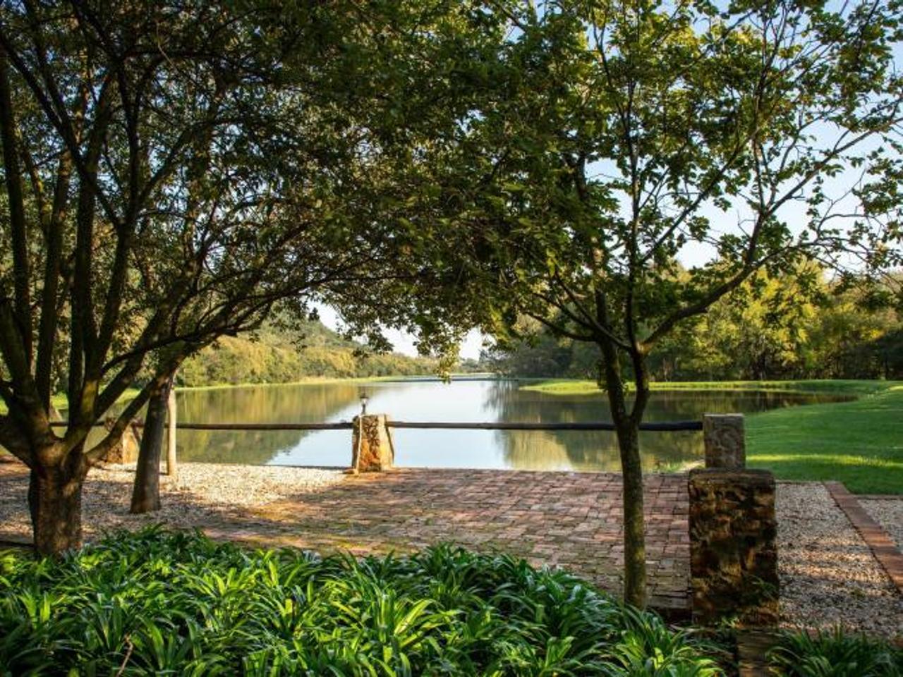 Brick terrace under shady trees looking out over a dam at Valley of the Rainbow Fly Fishing Estate near Dullstroom