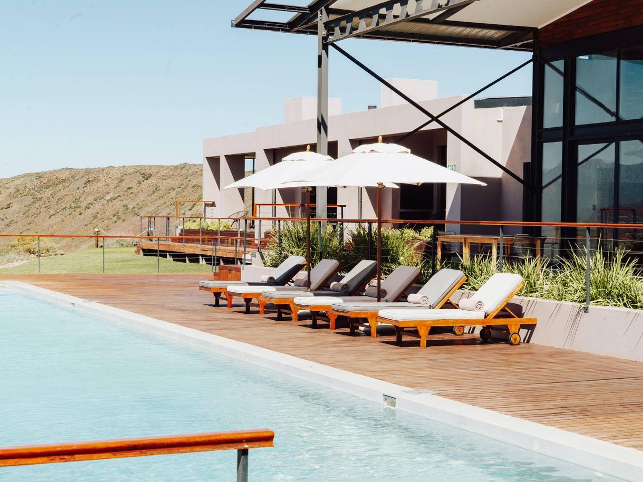 Sun loungers and umbrellas on a wooden deck beside the 25-metre pool at Khanyisa Mountain Lodge near Robertson