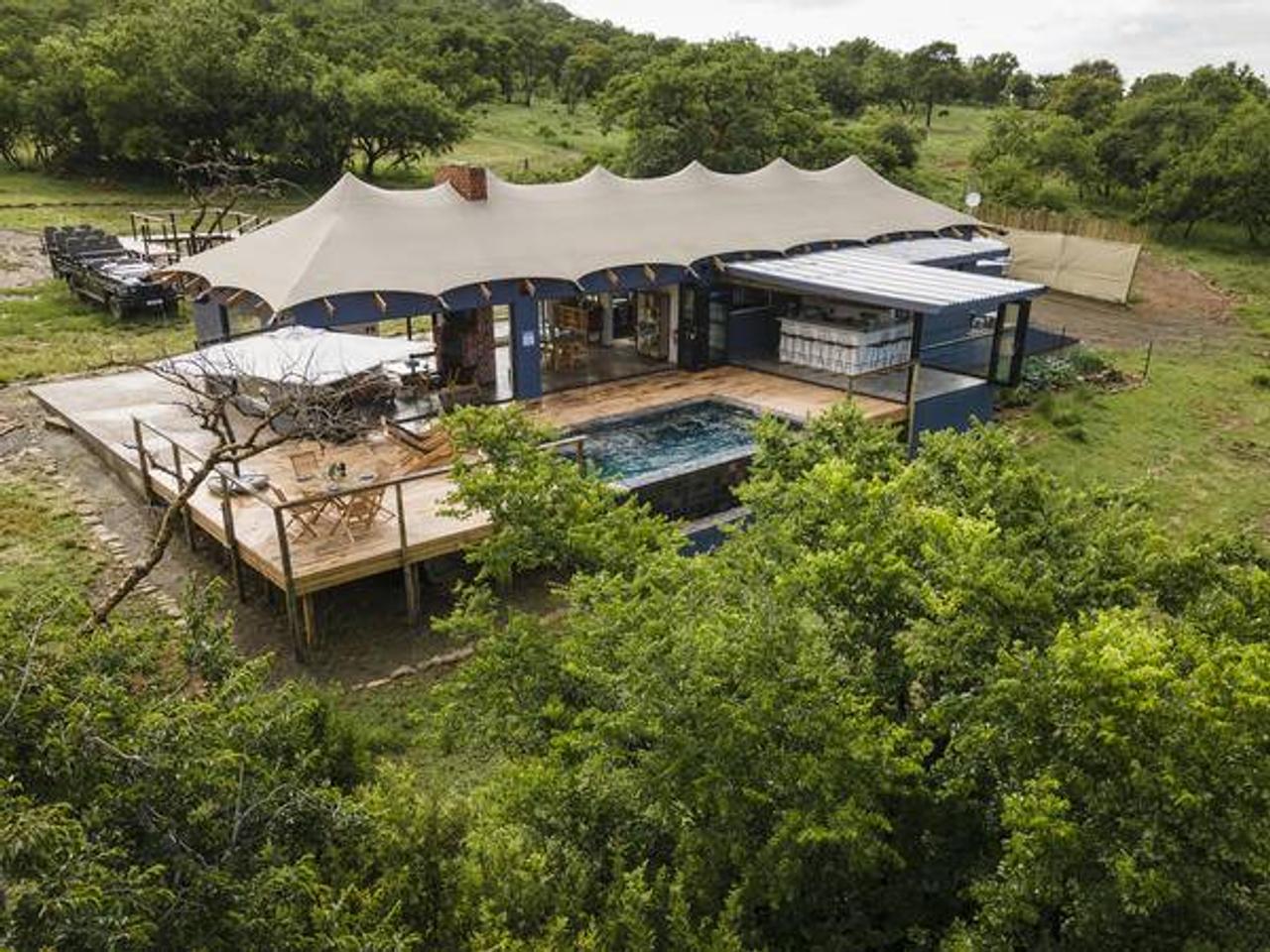 Aerial view of Sasi Bush Lodge’s main tented building, with a wooden deck and pool in the bush of the Northern Drakensberg