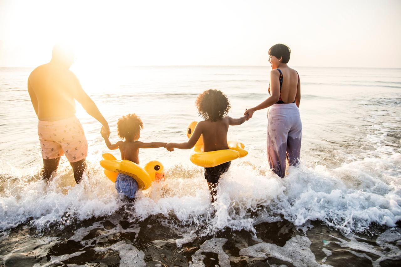 Family holding hands as they walk into the sea