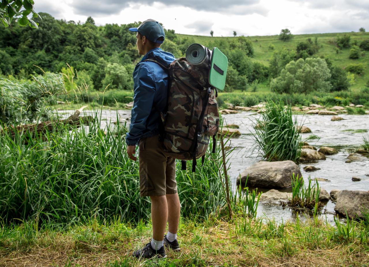 Hiker with a backpack looking out over a river