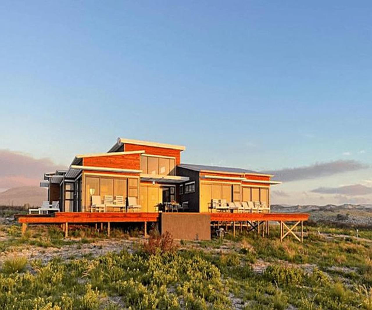 Walker Bay Dunes Lodge between Stanford and Gansbaai, a modern lodge with a raised wooden deck in coastal fynbos at sunset