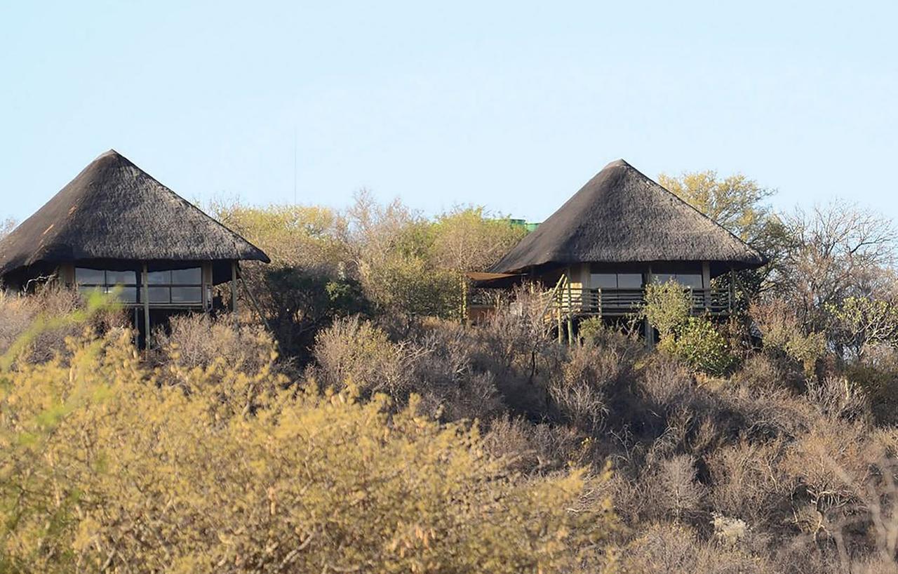 Two thatched lodge buildings on a bushveld hillside at Thulani Game Lodge and Eco Estate, Waterberg