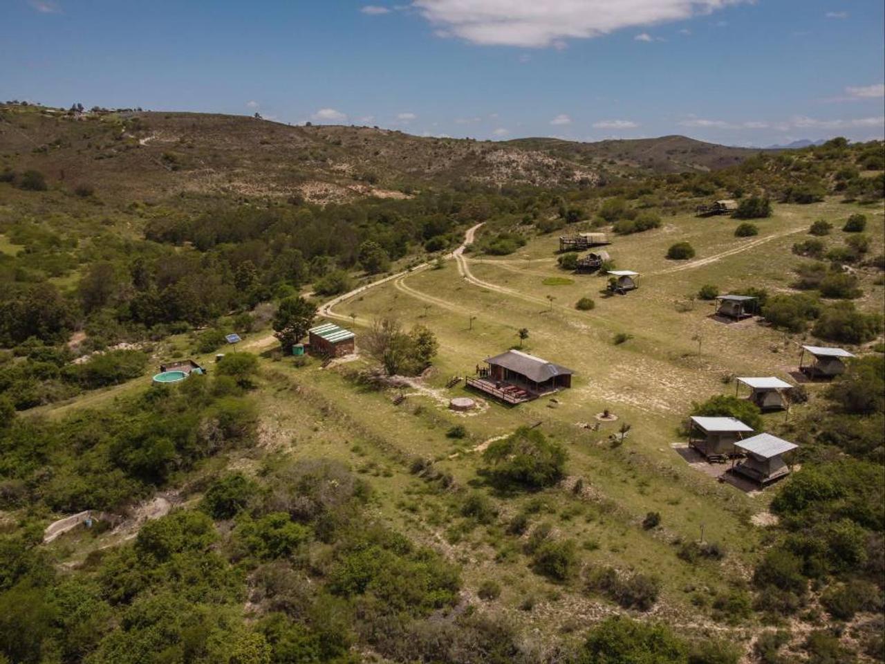 Aerial view of Pabala Private Nature Reserve near Jeffreys Bay, showing the family tents and a pool spread across a grassy valley