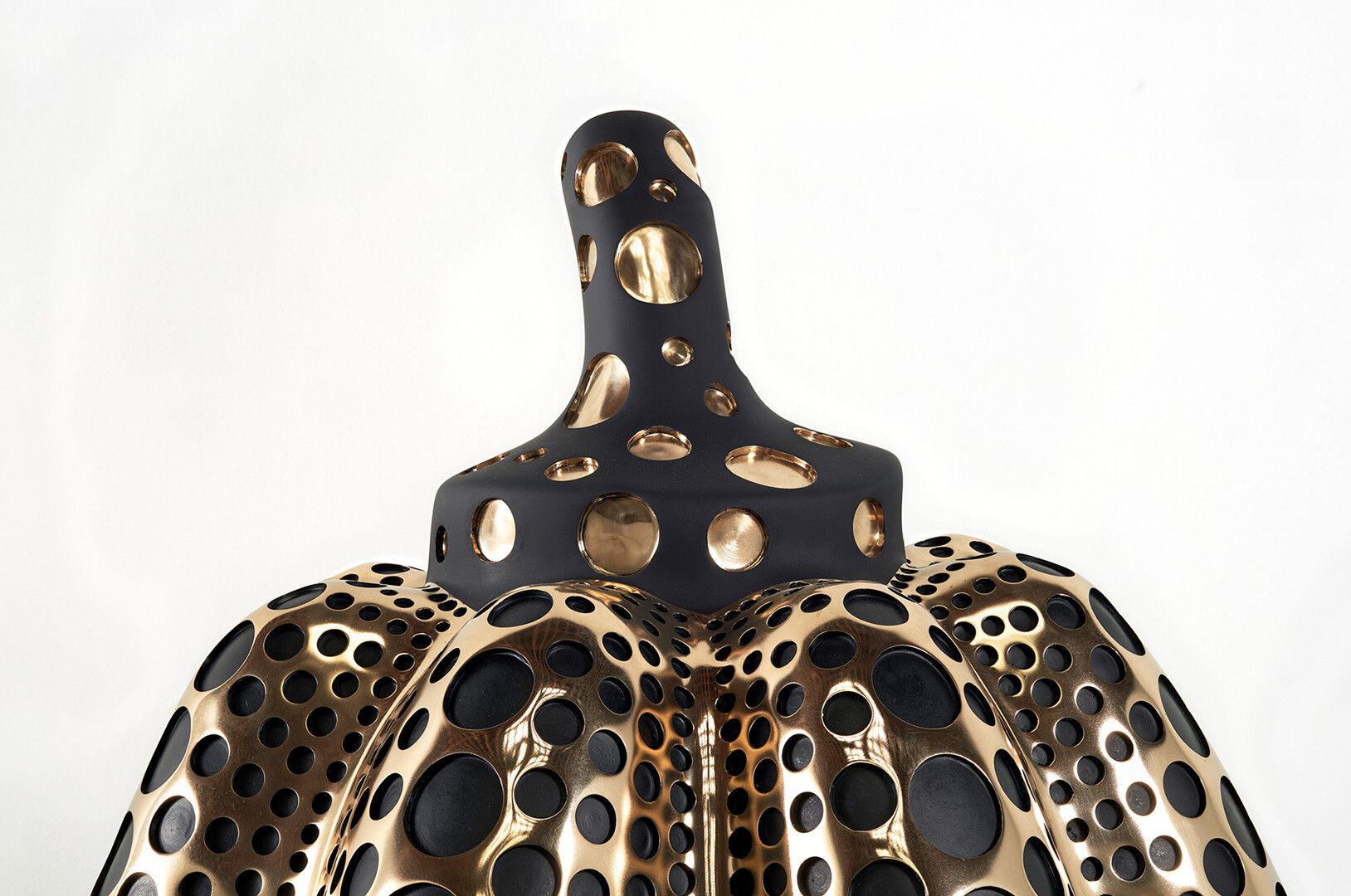 A detail view of a mirror polished bronze, dye, and acrylic lacquer sculpture by Yayoi Kusama, titled Pumpkin (M), dated 2016.