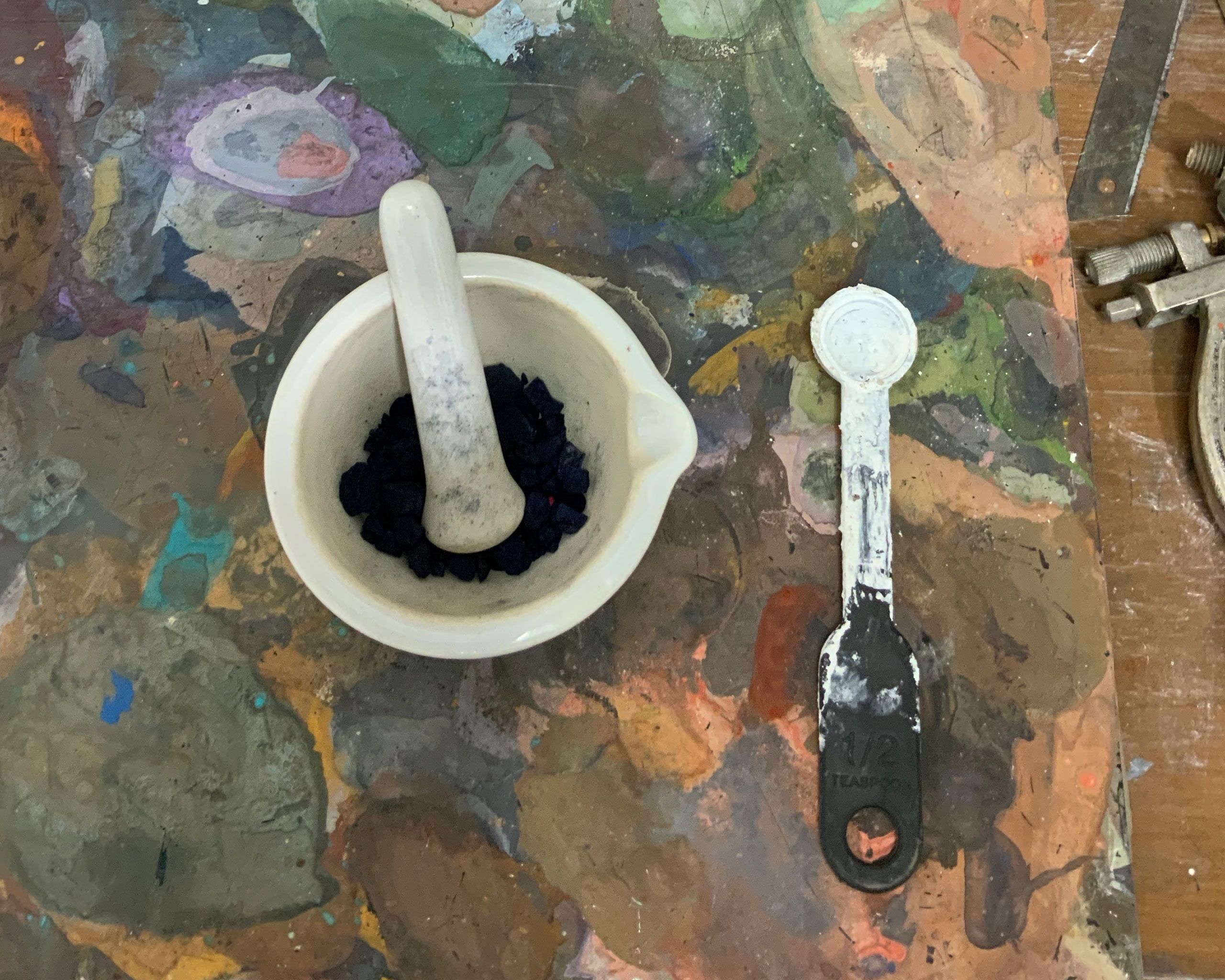 A photograph of a mortar and pestle Baliga uses to grind rough pigments and a measuring spoon in Baliga’s studio, dated 2022.