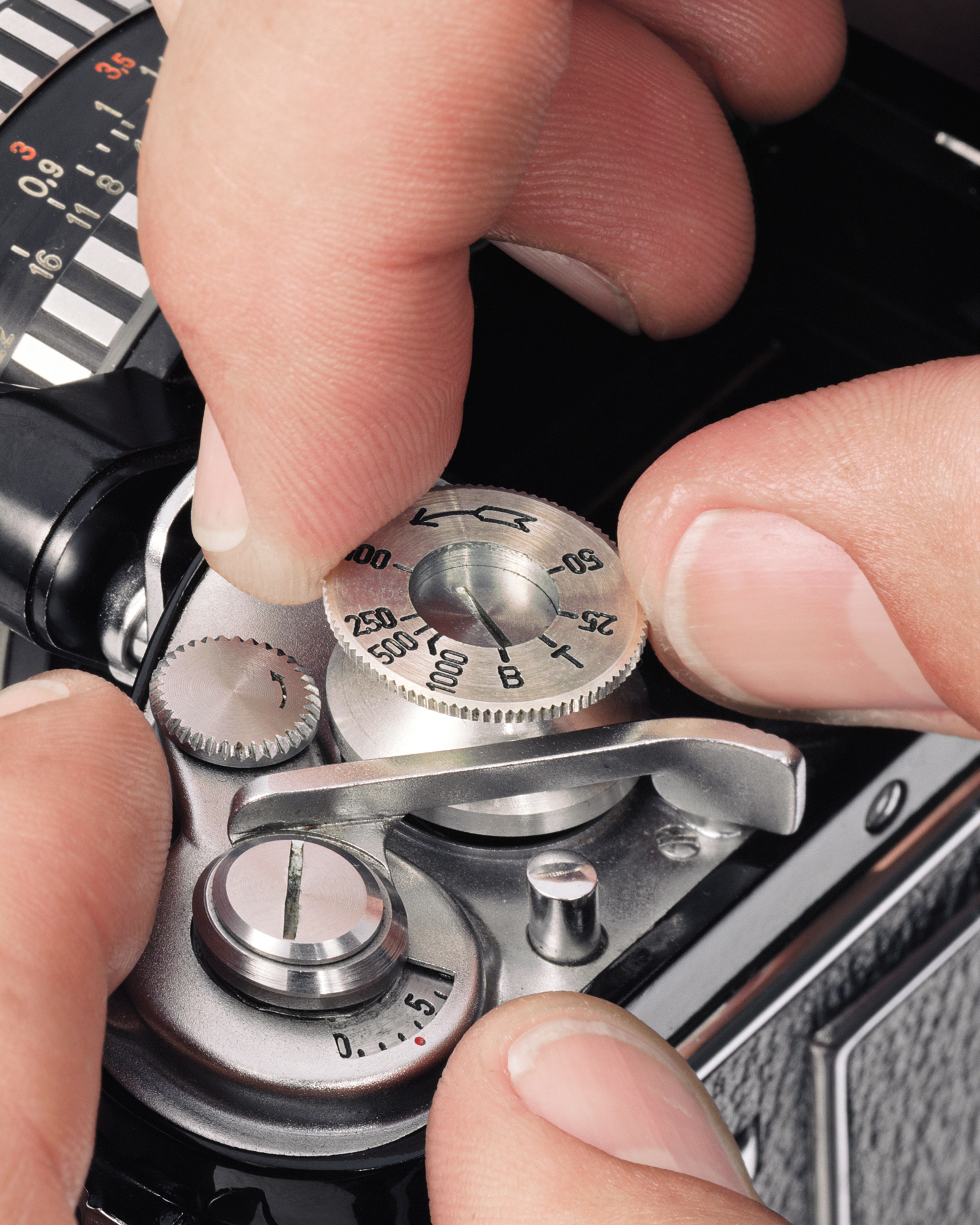 A photograph by Christopher Williams depicting a close up of fingers changing the dial on a camera, titled Fig. 4: Changing the shutter speed‚Ä¶, dated 2012.