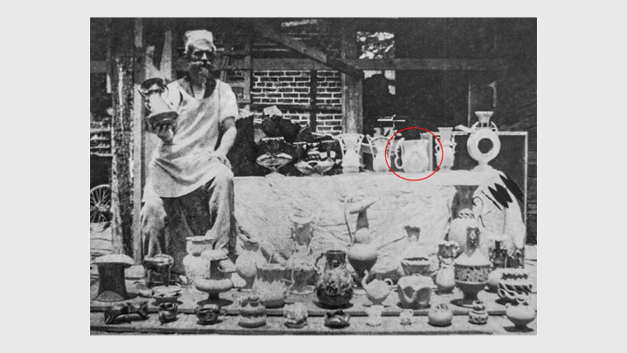 George Ohr with a selection of his pots, n.d. Large pitcher, 1898-1900 is visible, unglazed, at center right.