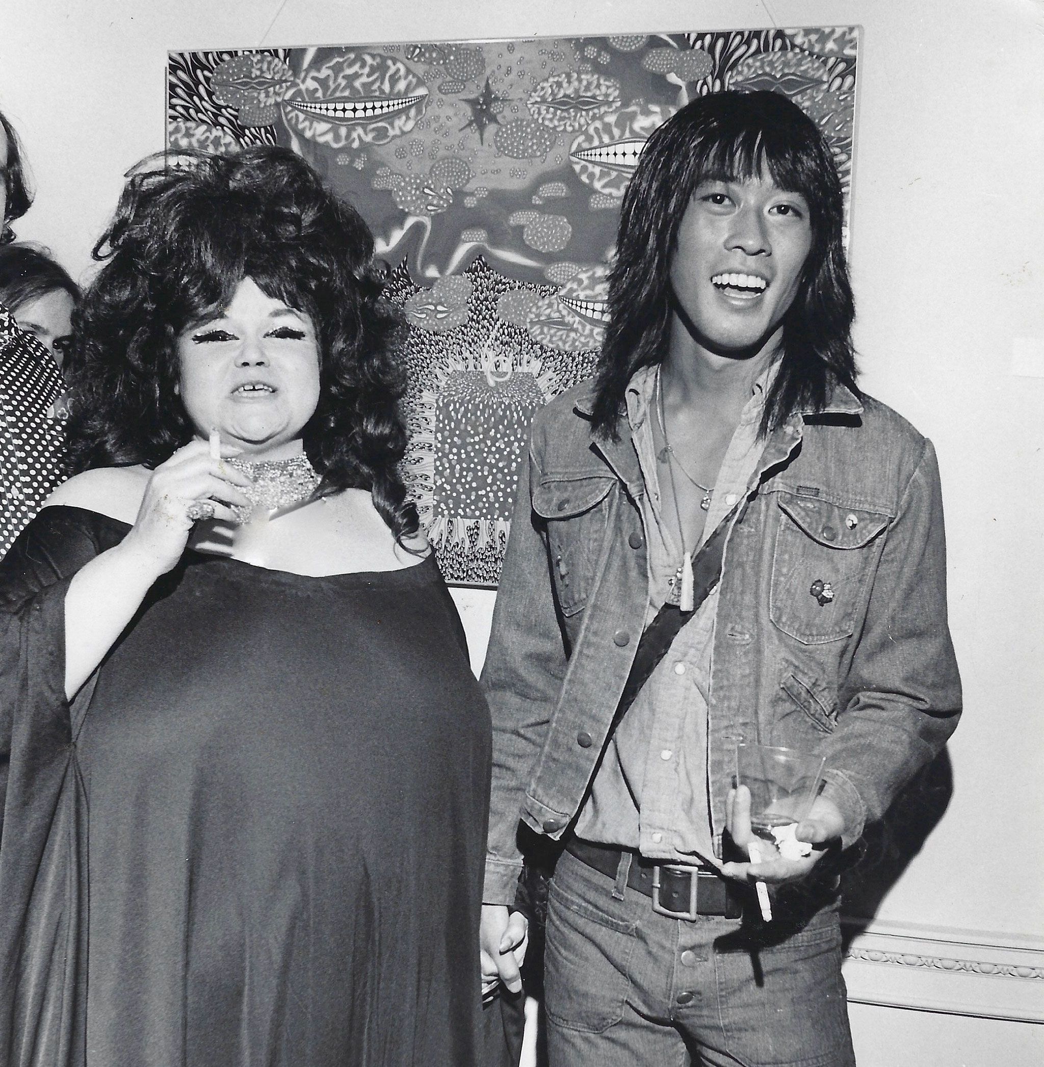 A photo of Andy Warhol's Superstar Tally Brown and Ching Ho Cheng in front of his painting Angel Head, in the 1970s.