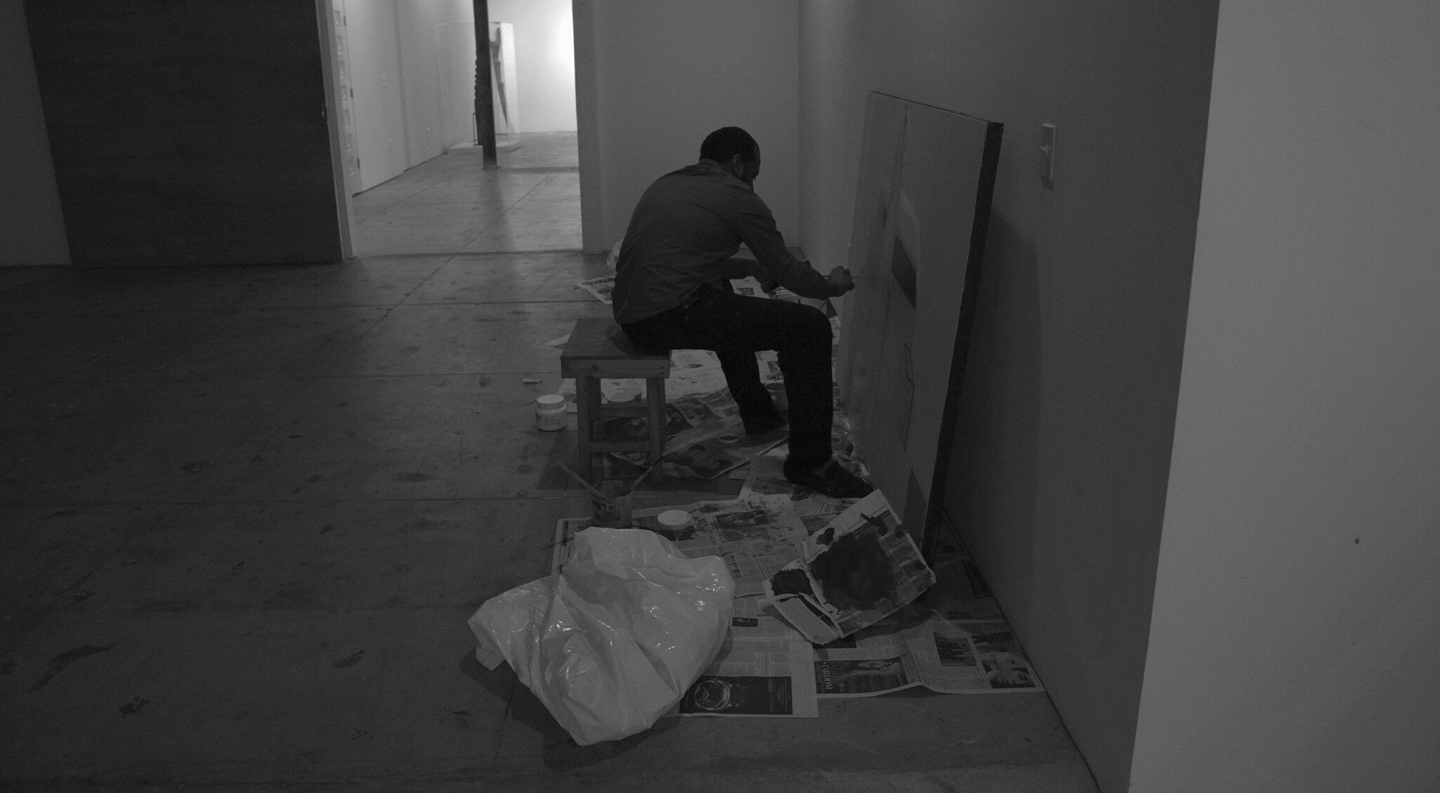 A photo of Noah Davis painting a canvas at The Underground Museum.