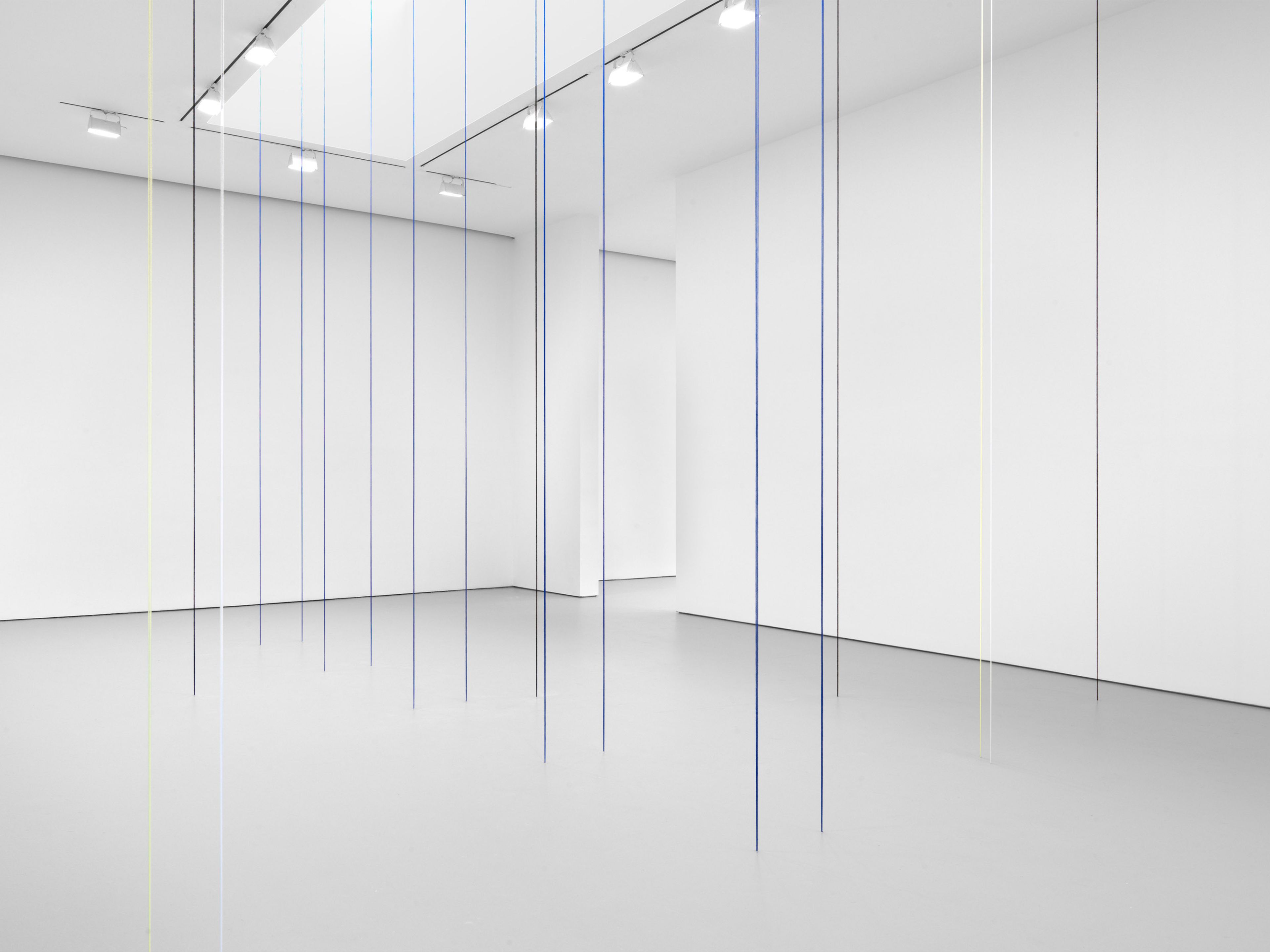 A black, blue, white, and light yellow acrylic yarn artwork by Fred Sandback, titled Untitled (Sculptural Study, Eighteen-part Architectonic Vertical Construction), 1987 and 2018.