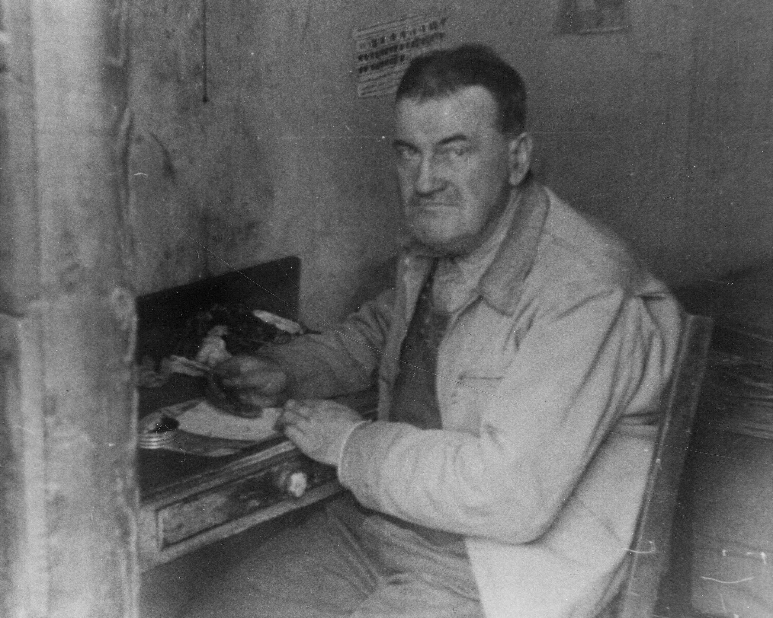 A photograph of James Castle at his workspace in his shed