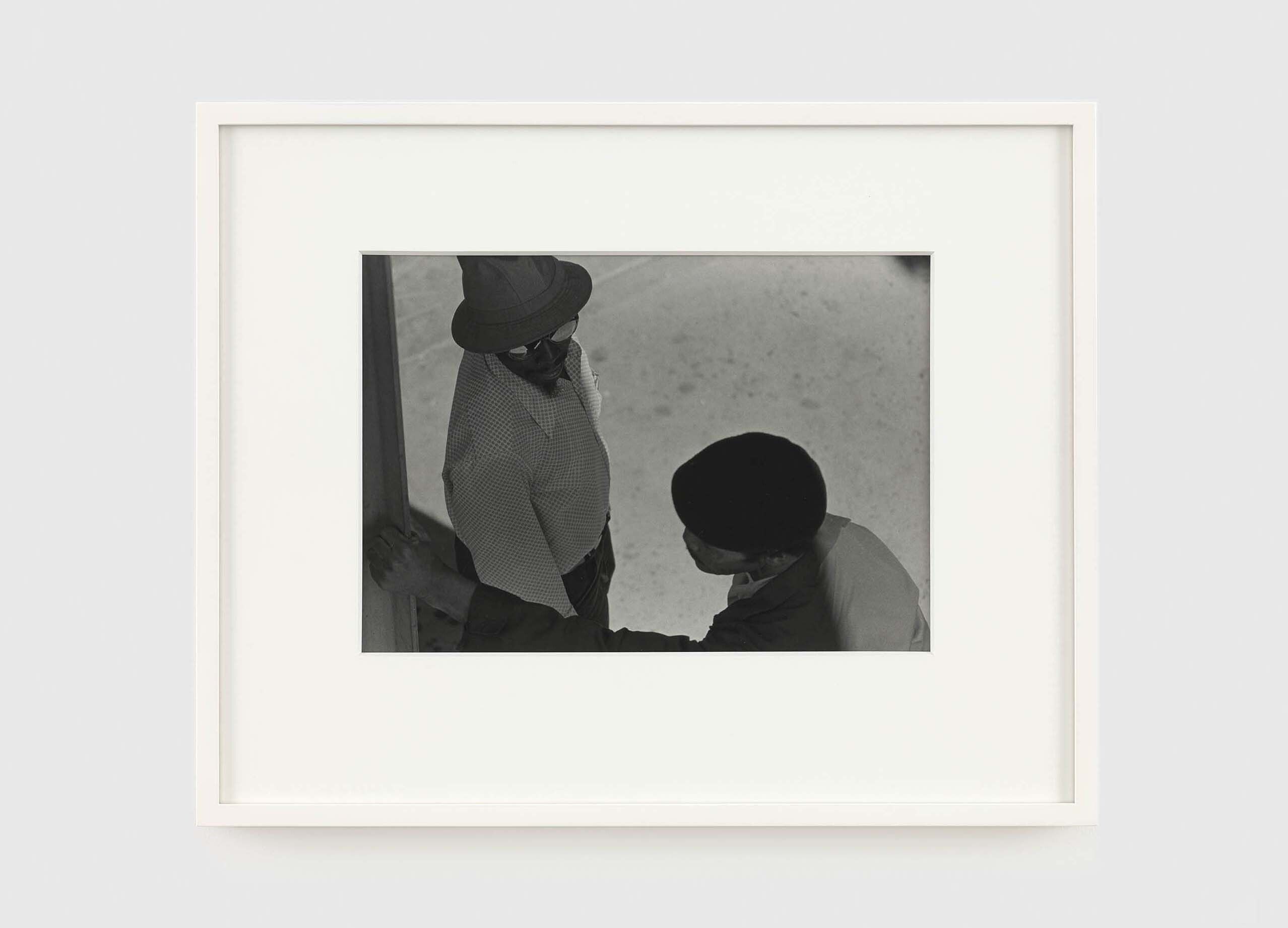 A photograph by Roy DeCarava, titled Two men talking, lampost, dated 1977.
