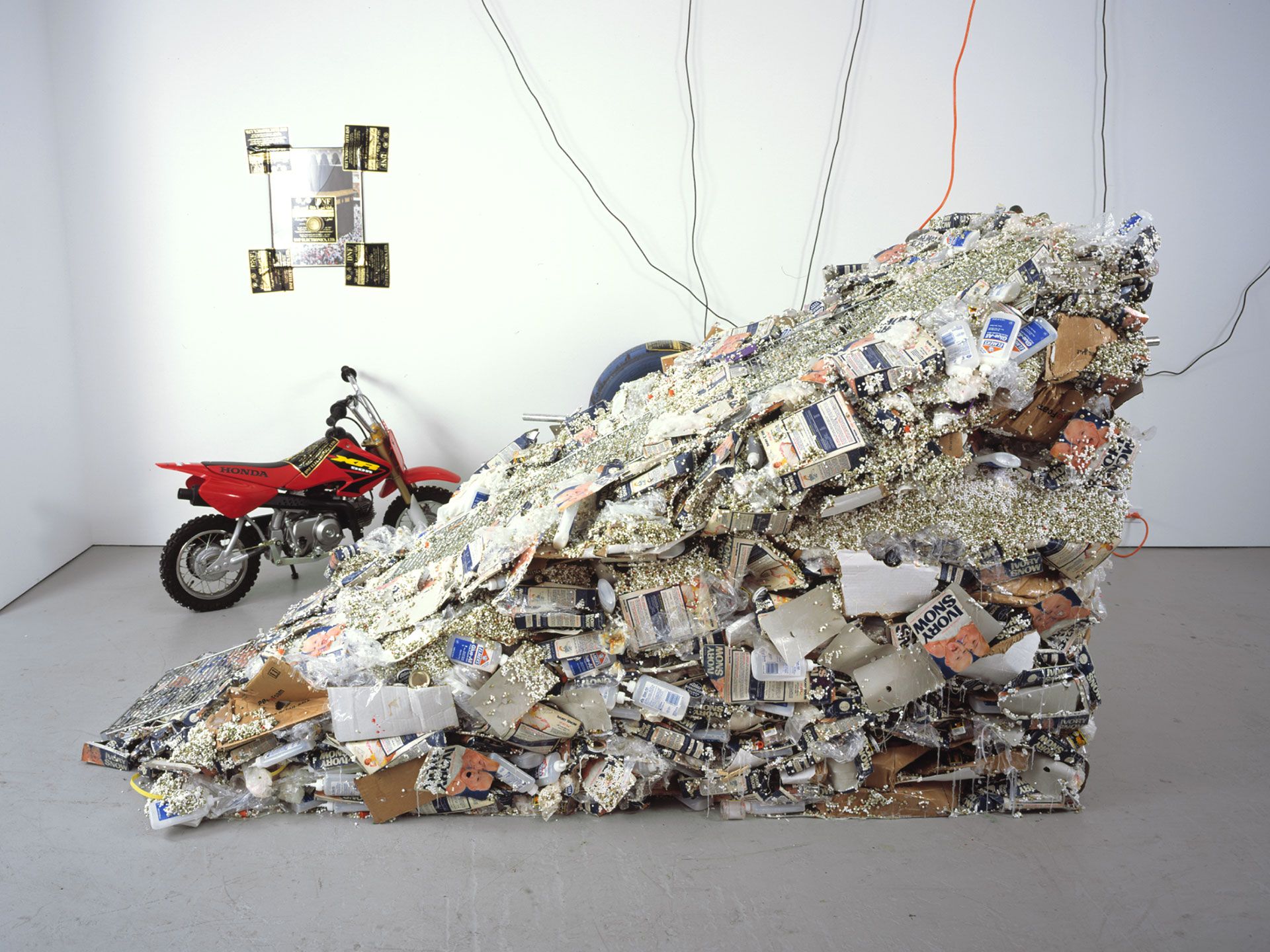 A sculpture by Jason Rhoades, titled PeaRoe Ramp (From Wastewedge, Part of Impetuous Process, 2002), with Embedded HiFi and Honda XR50, dated 2003.