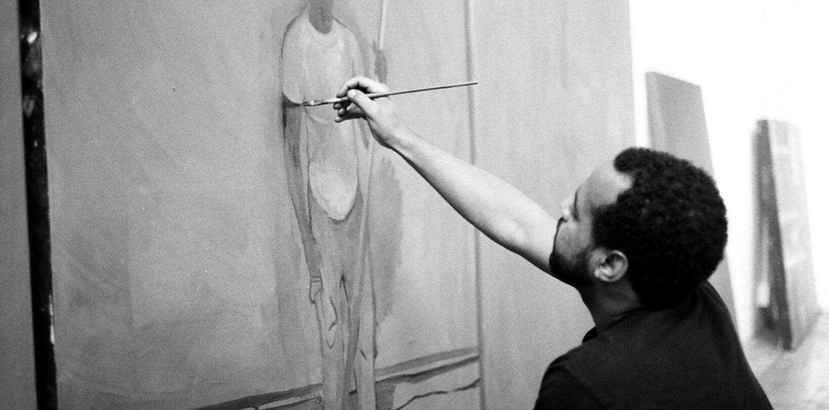 A photo of Noah Davis painting a figure.