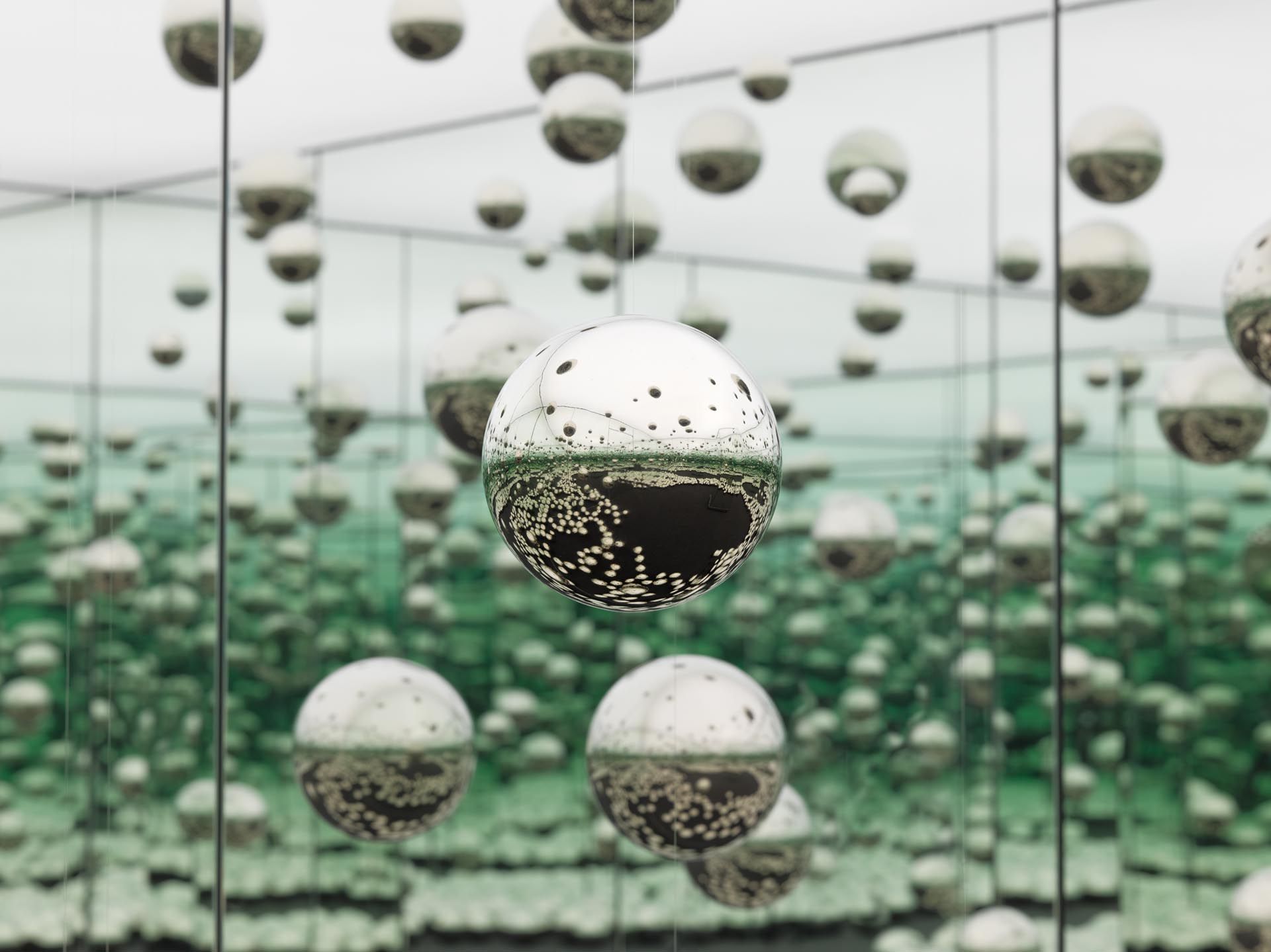 An experiential installation by Yayoi Kusama, comprised of mirrors, wood, LED lighting system, metal, steel balls, and carpeting, titled Infinity Mirrored Room - Let's Survive Forever, dated 2017.