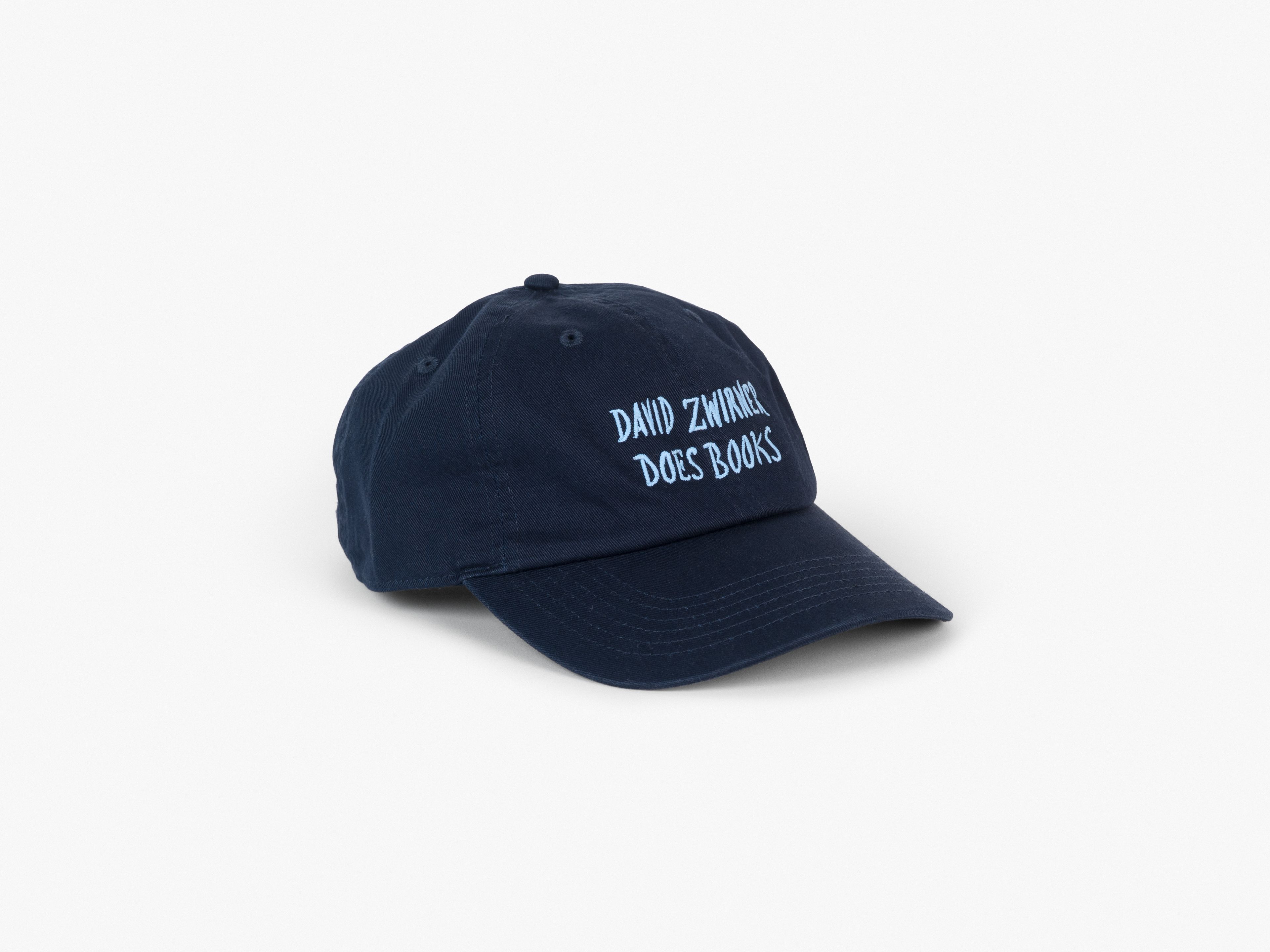 A classic six-panel cap in navy cotton twill, featuring embroidered handwriting by Marcel Dzama reading "David Zwirner Does Books"