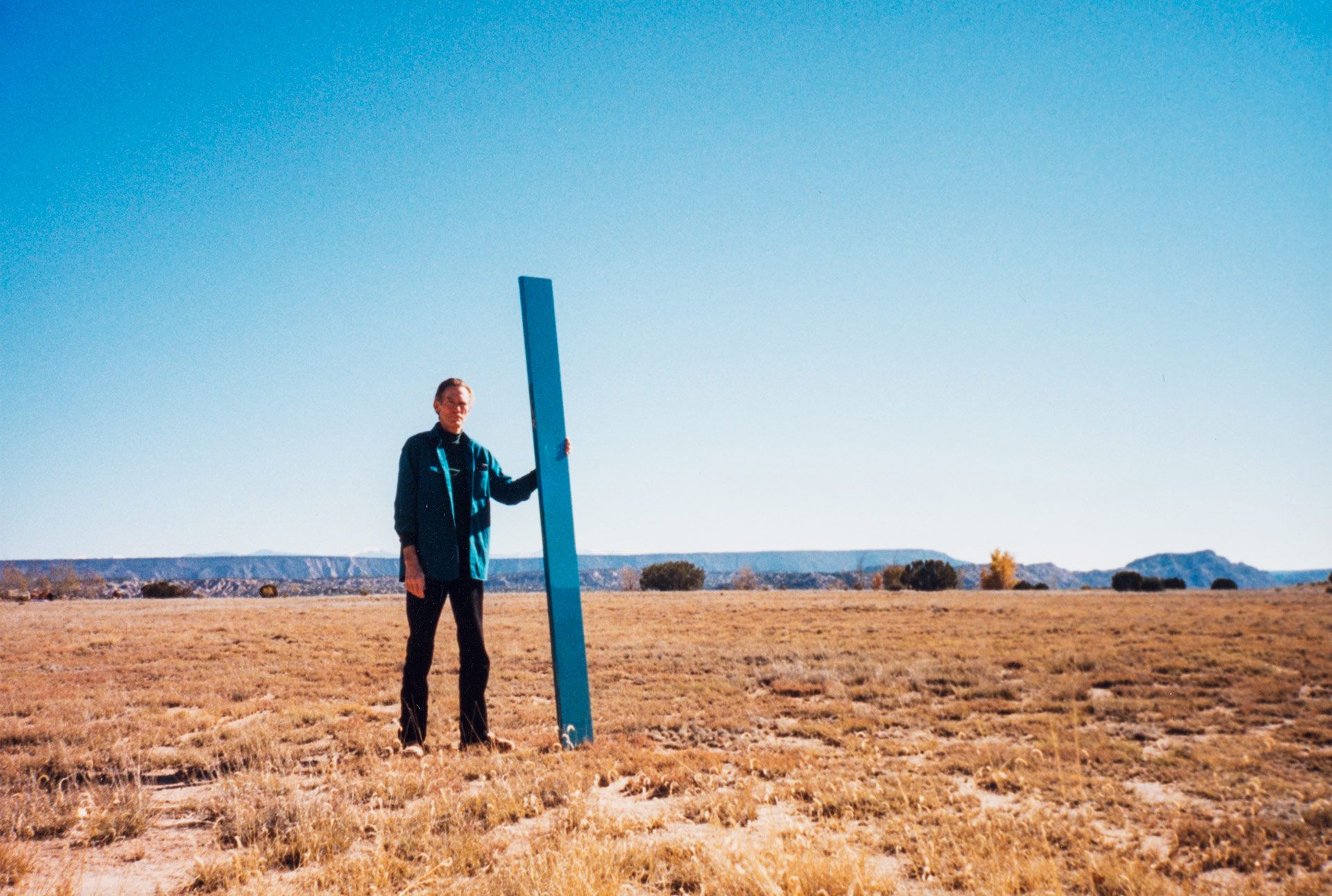 A photo of John McCracken with one of his plank sculptures, dated 1996.