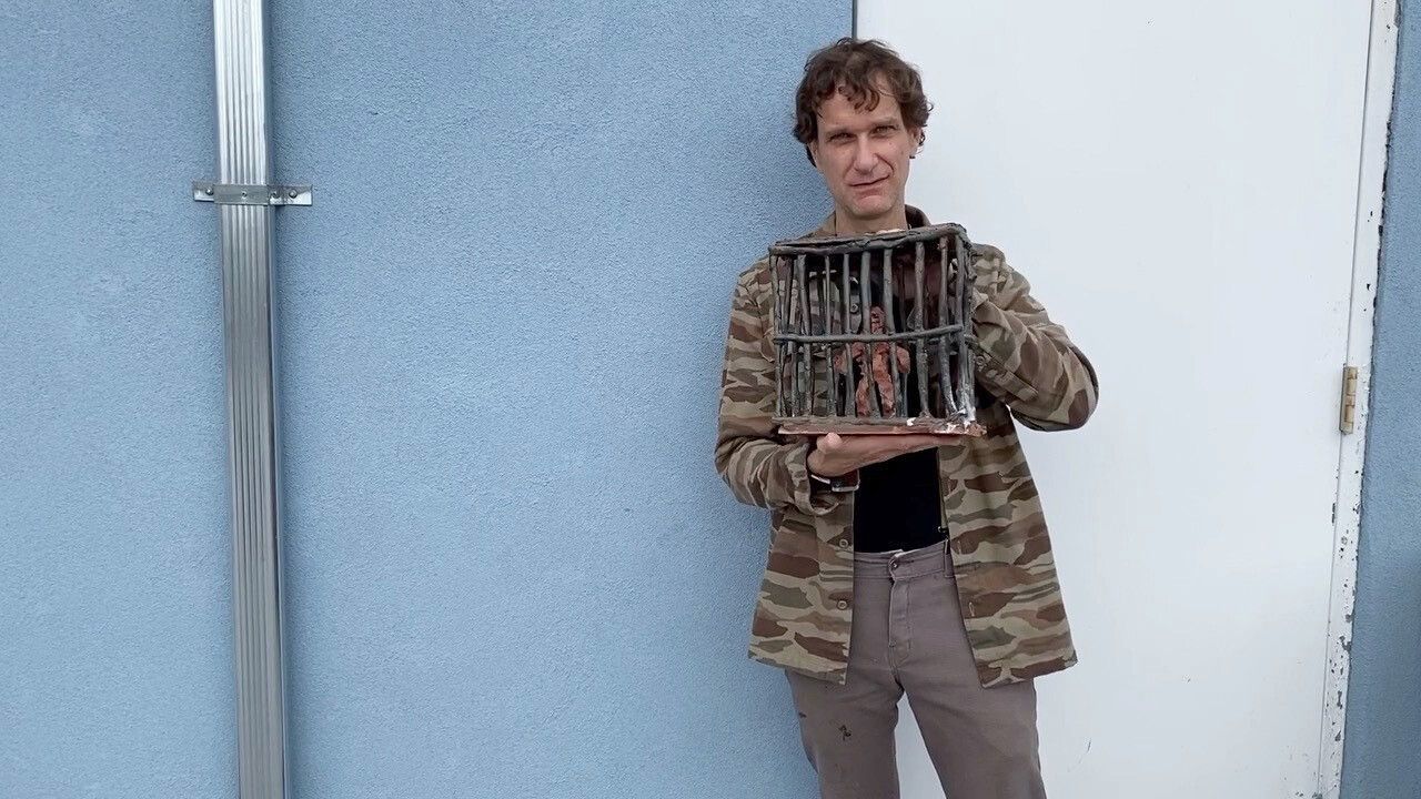 A photo of Josh Smith holding one of his ceramic prison sculptures.