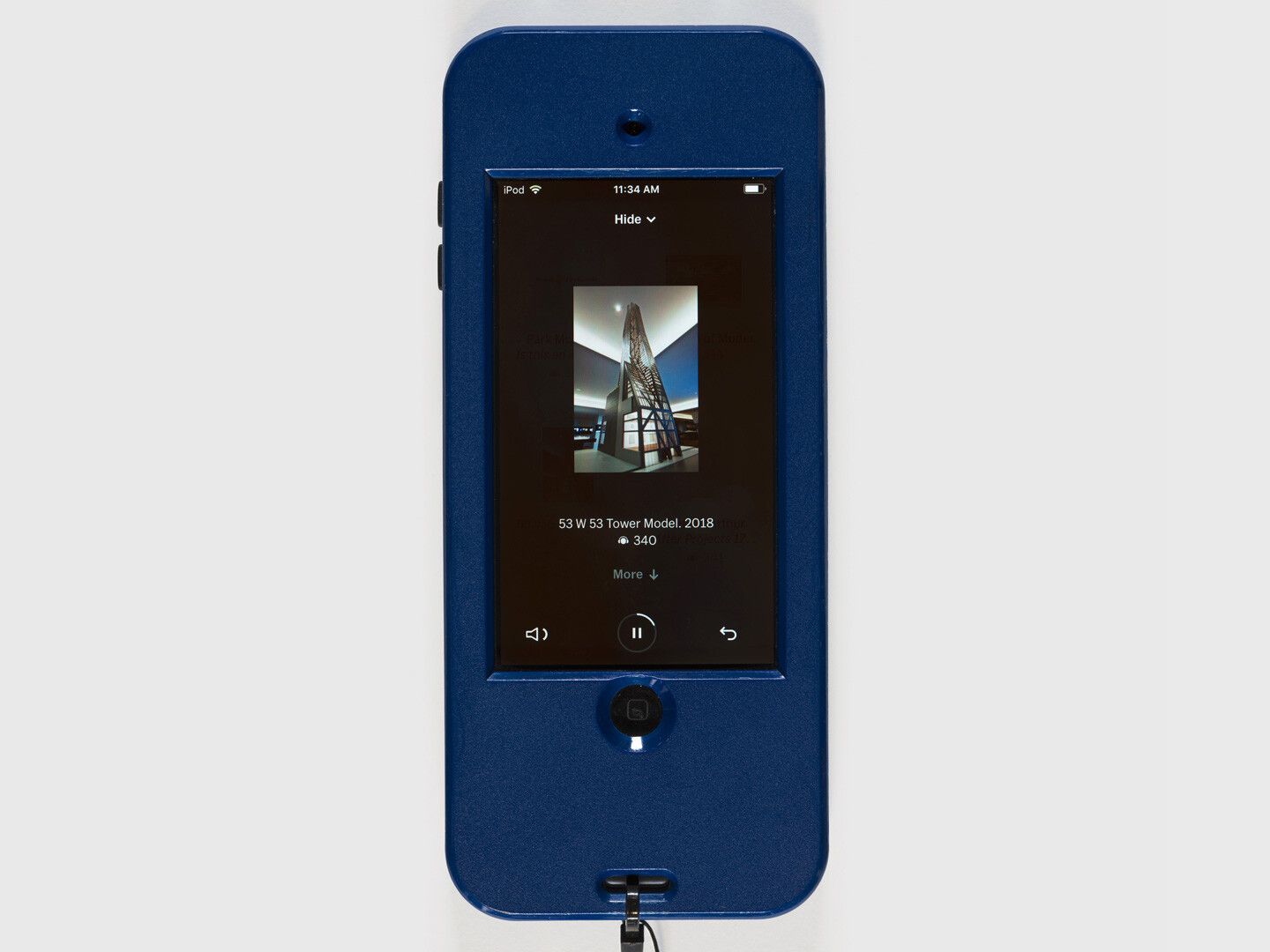 A MoMA Audio listening device (an iPod in a blue case). On the screen, the current track is 340, titled “53 W 53 Tower Model, 2018.” There is a thumbnail image of the tower model as well as buttons to adjust the volume, pause, and restart.