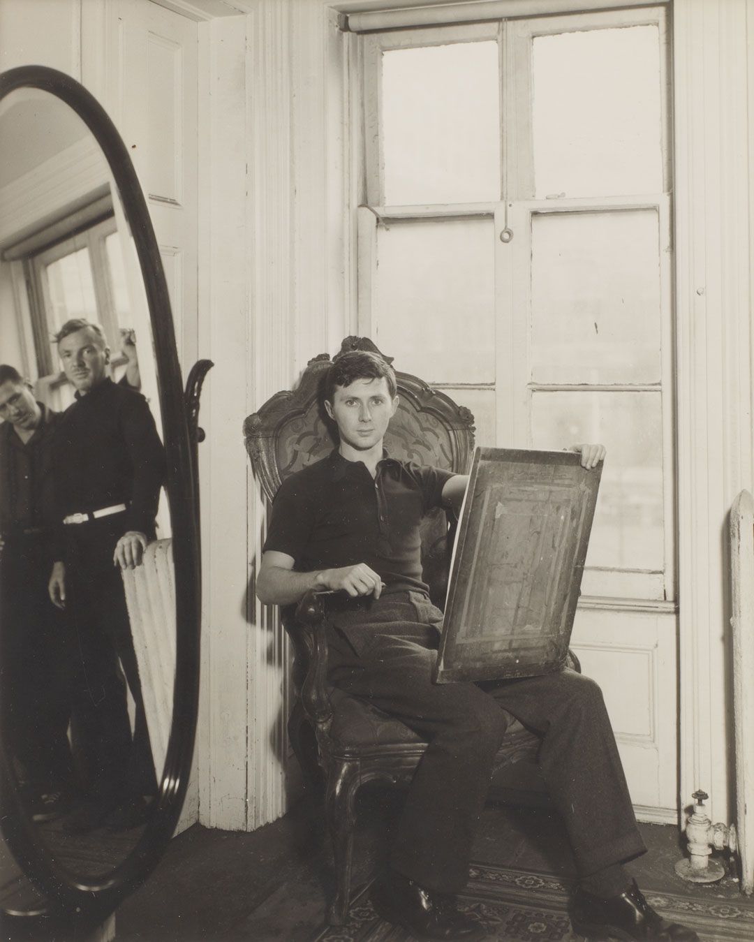 A gelatin silver print by George Platt Lynes, titled George Tooker at 5 St. Luke's Place with Paul Cadmus and Jared French in Mirror, circa 1949.
