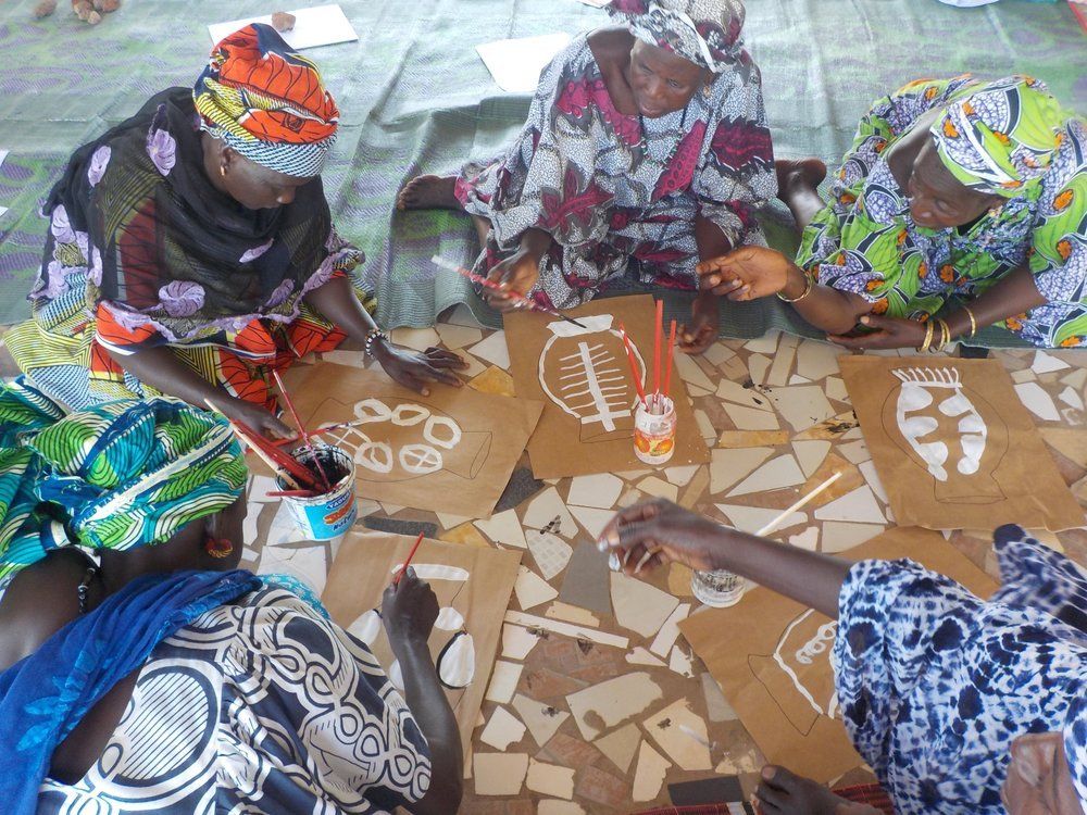 A photograph of Sinthian women making designs for wood-fired ceramics by Dana Louis, undated.