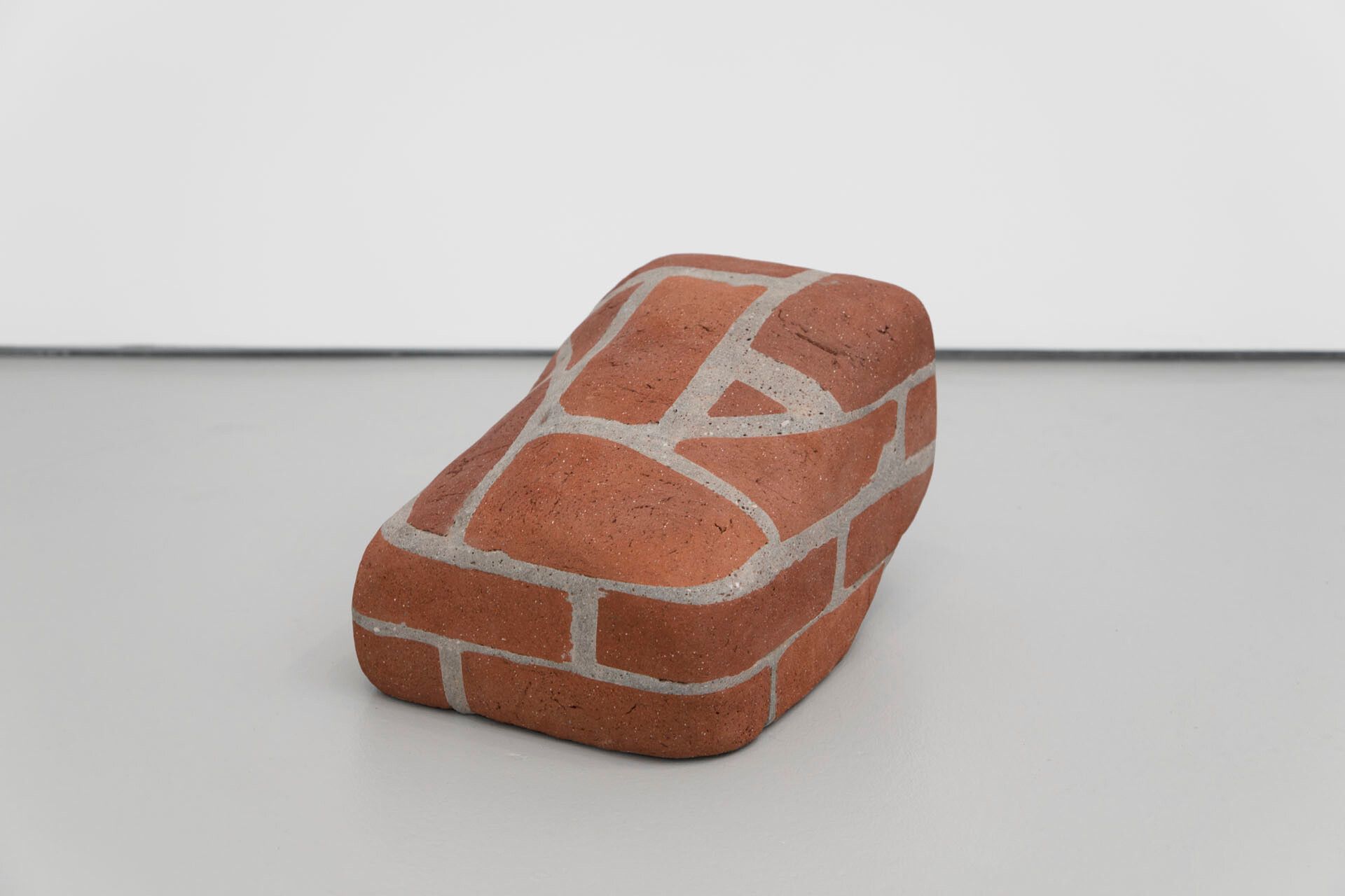 A sculpture by Gordon Hall, titled Kneeling (Brick Object) (II), dated 2018.
