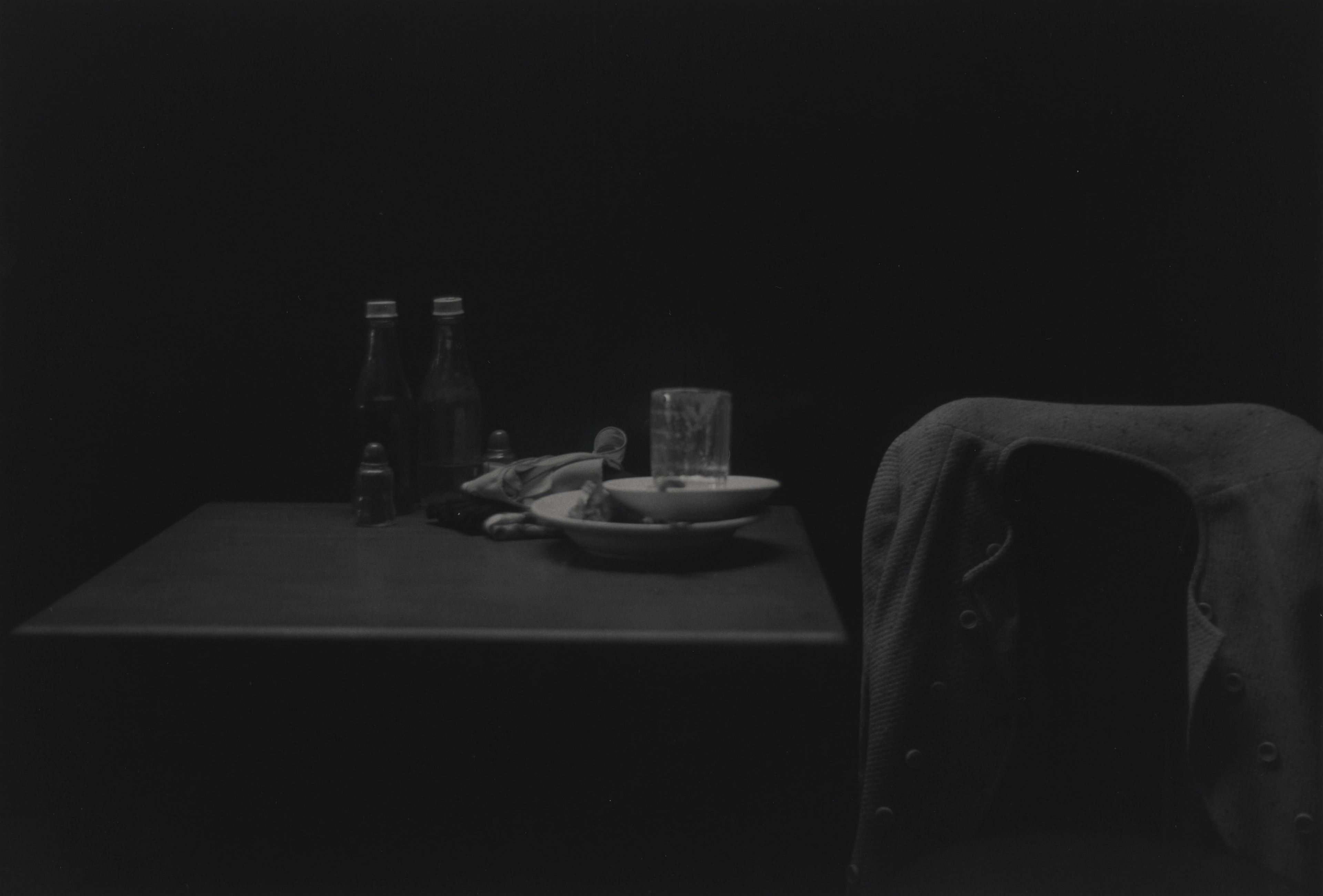 A silver gelatin print by Roy DeCarava, titled Catsup bottles, table and coat, dated 1952.