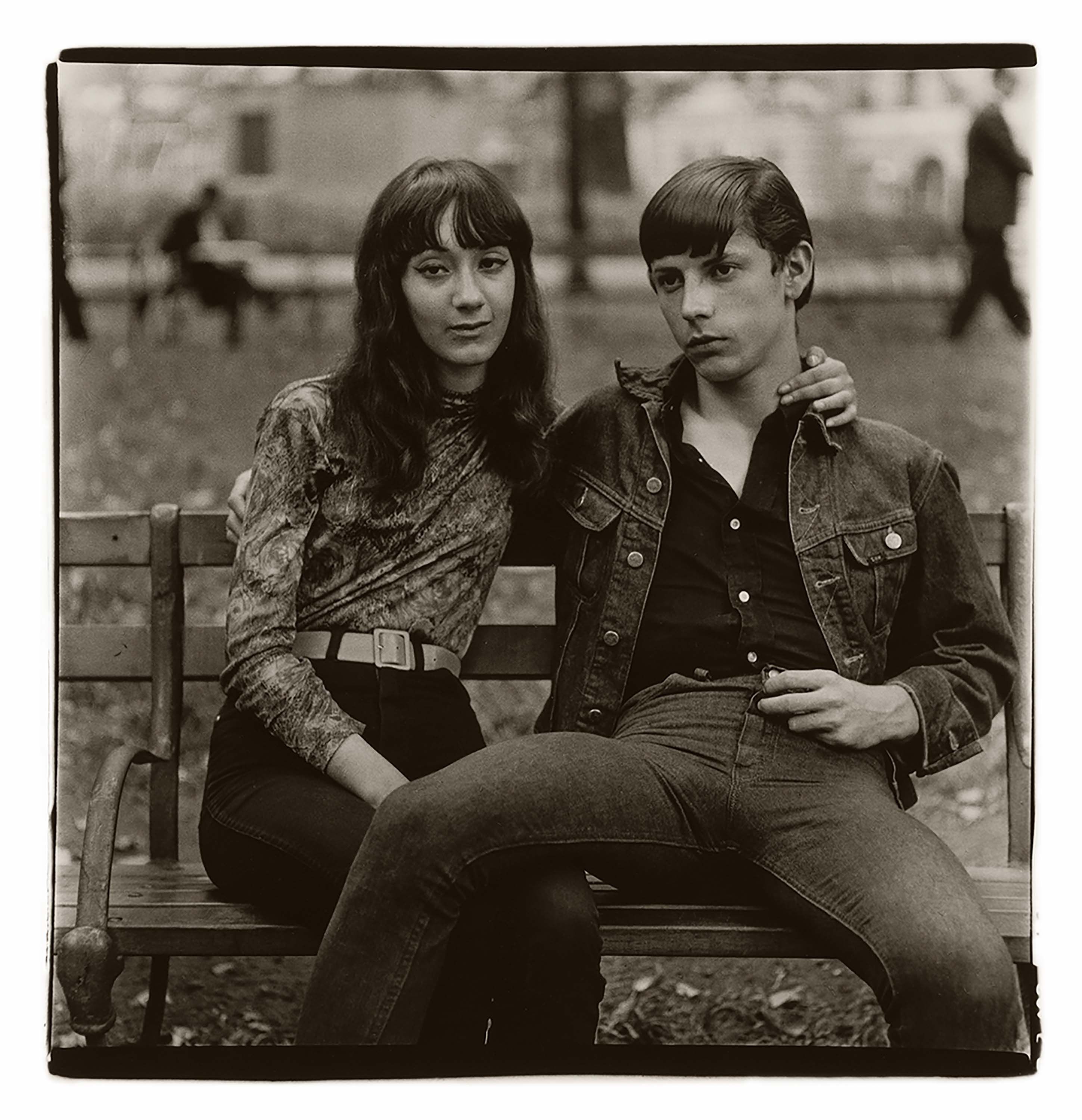 A photograph by Diane Arbus, titled Young couple on a bench in Washington Square Park, N.Y.C. 1965, dated 1965.