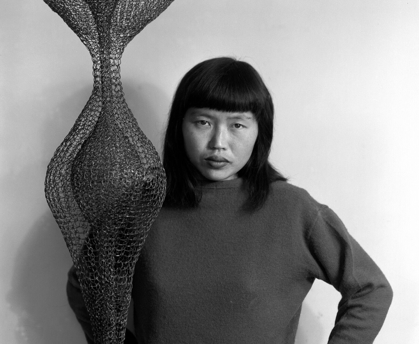 A photo of Ruth Asawa with her work "Hanging Sculpture," dated 1951. 