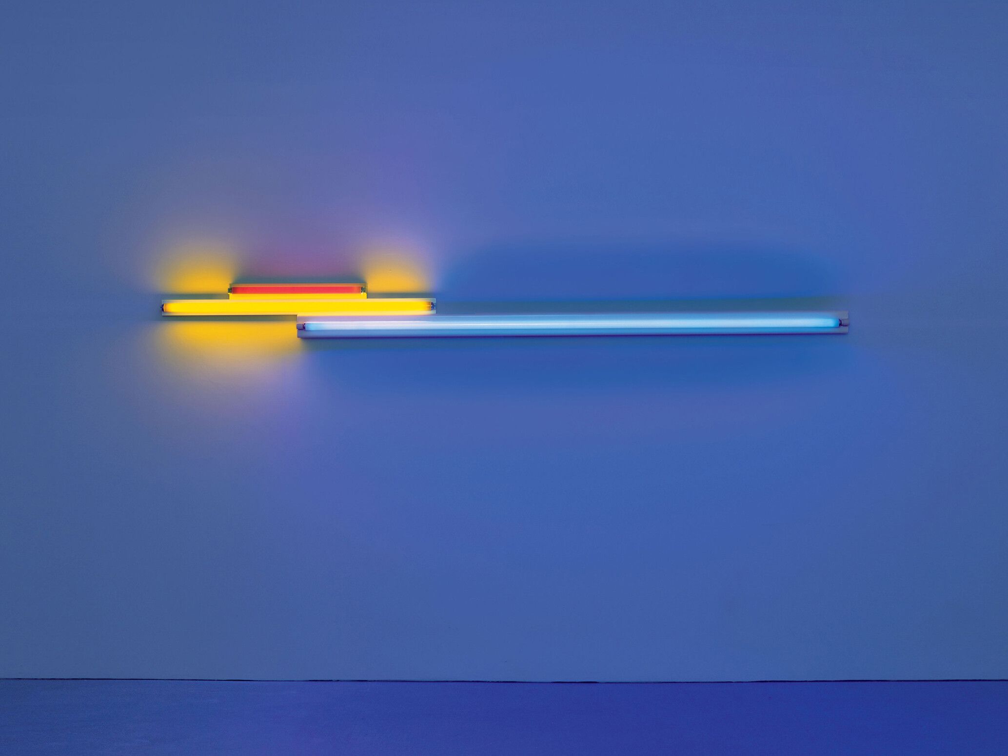 A red, yellow, and blue fluorescent light sculpture by Dan Flavin, titled untitled (in memory of "Sandy" Calder) V, dated 1977.