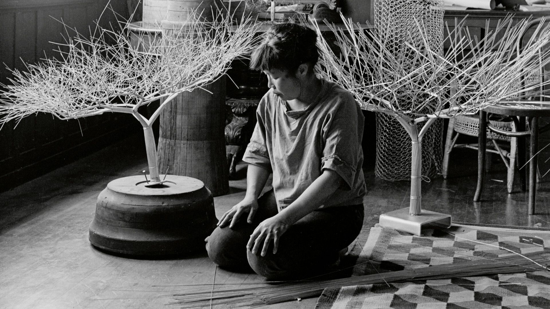 A photograph by Imogen Cunningham of Ruth Asawa in her dining room with tied-wire sculptures, dated 1963.