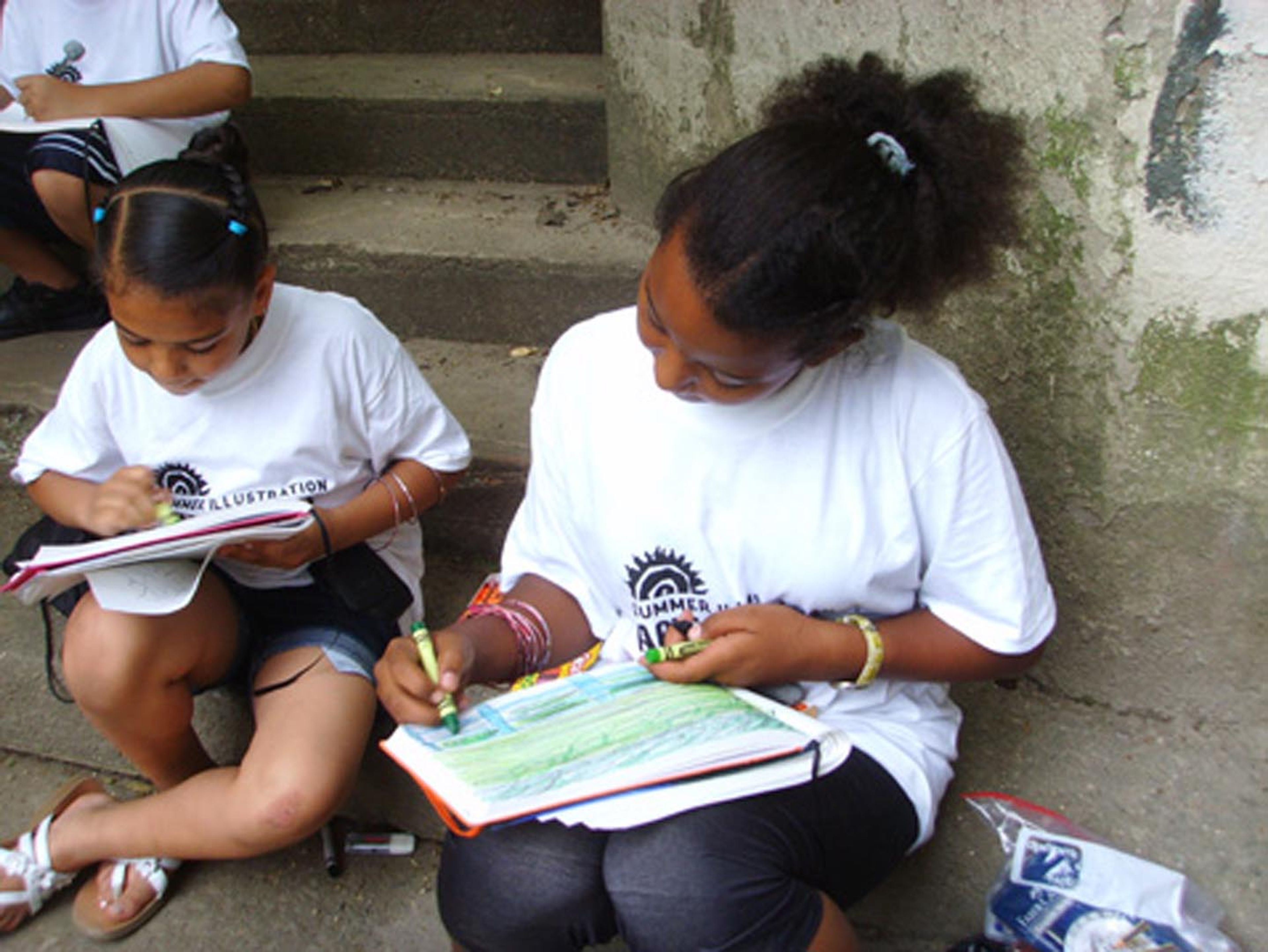 Two girls sitting on the steps, drawing in a colorbook.