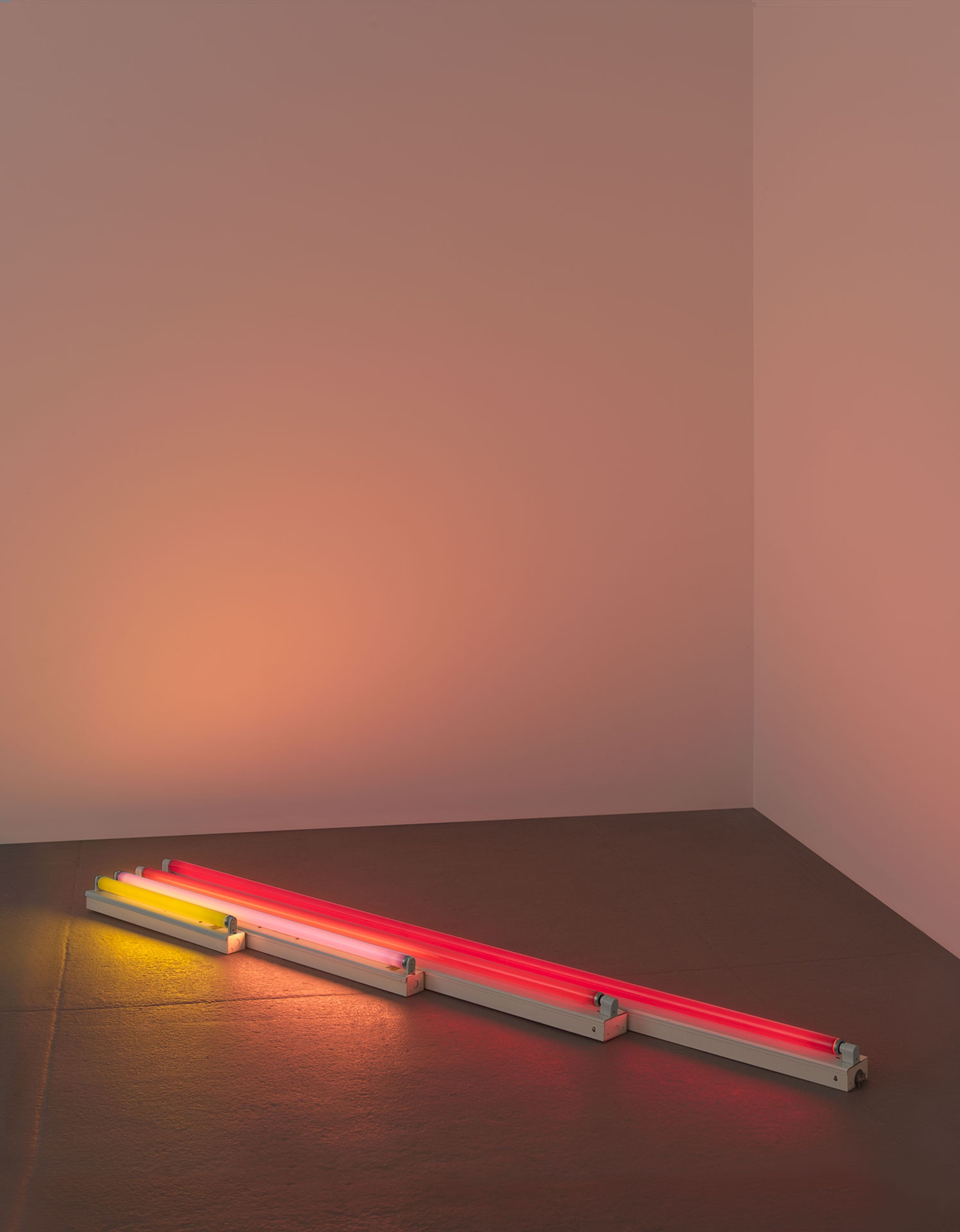 A sculpture in yellow, pink, and red fluorescent light by Dan Flavin, titled gold, pink and red, red, dated 1964.