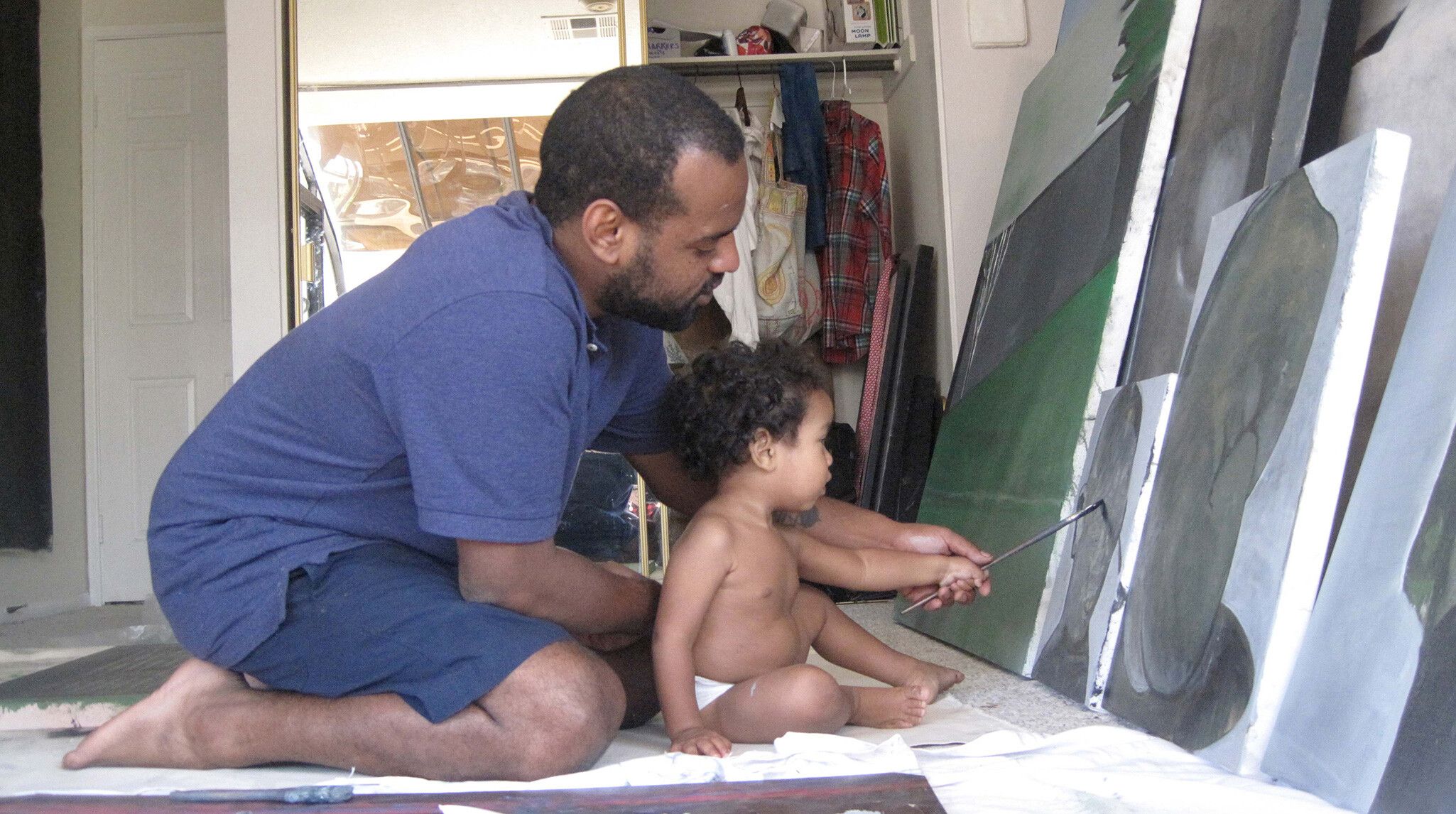A photo of Noah Davis painting with his son Moses.