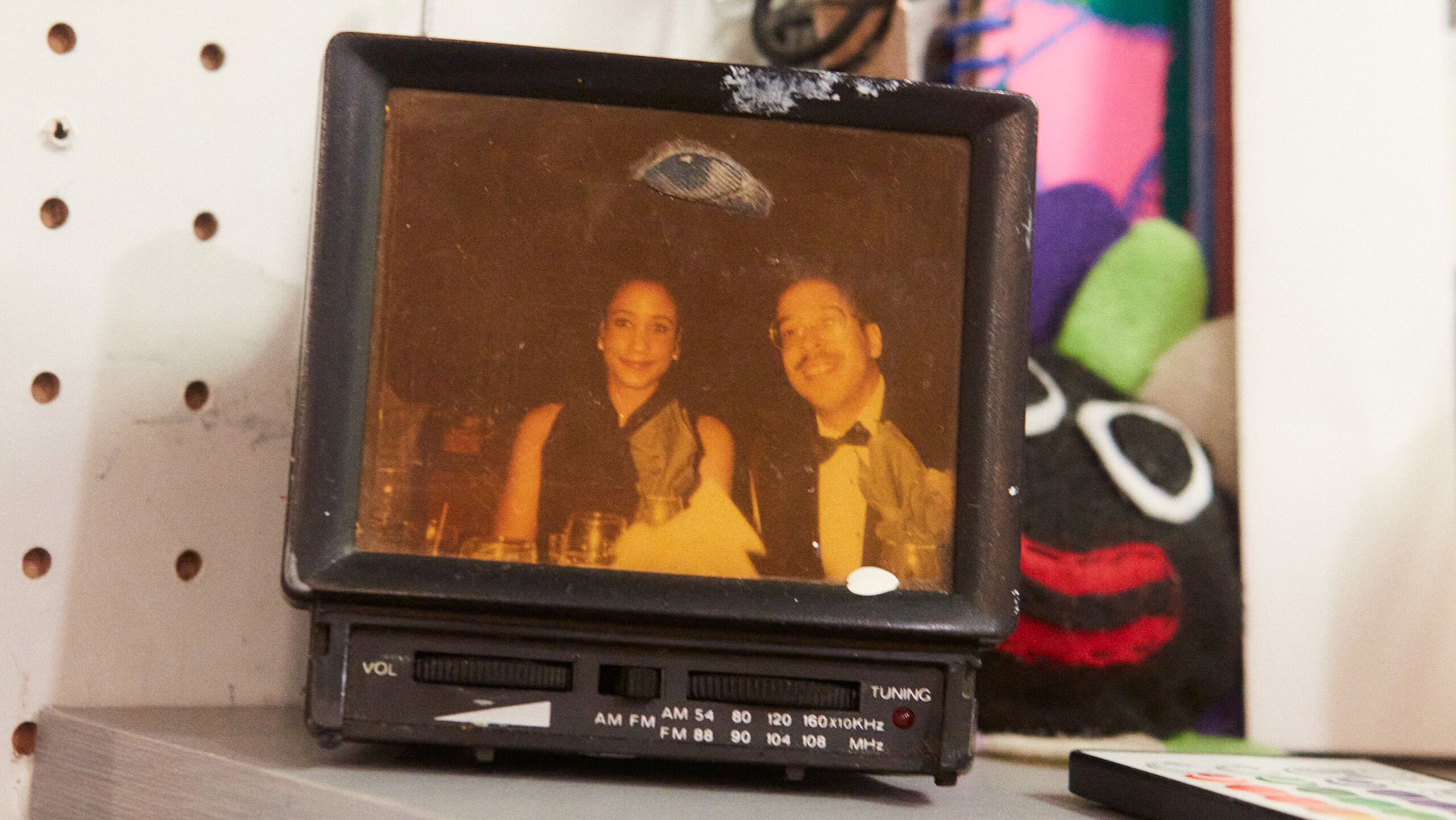 A photograph of Diuguid’s parents attached to a TV-shaped radio gifted to her by her father, with John F. Kennedy’s eyeball pasted to the photo, by Rafael Rios, dated 2022.